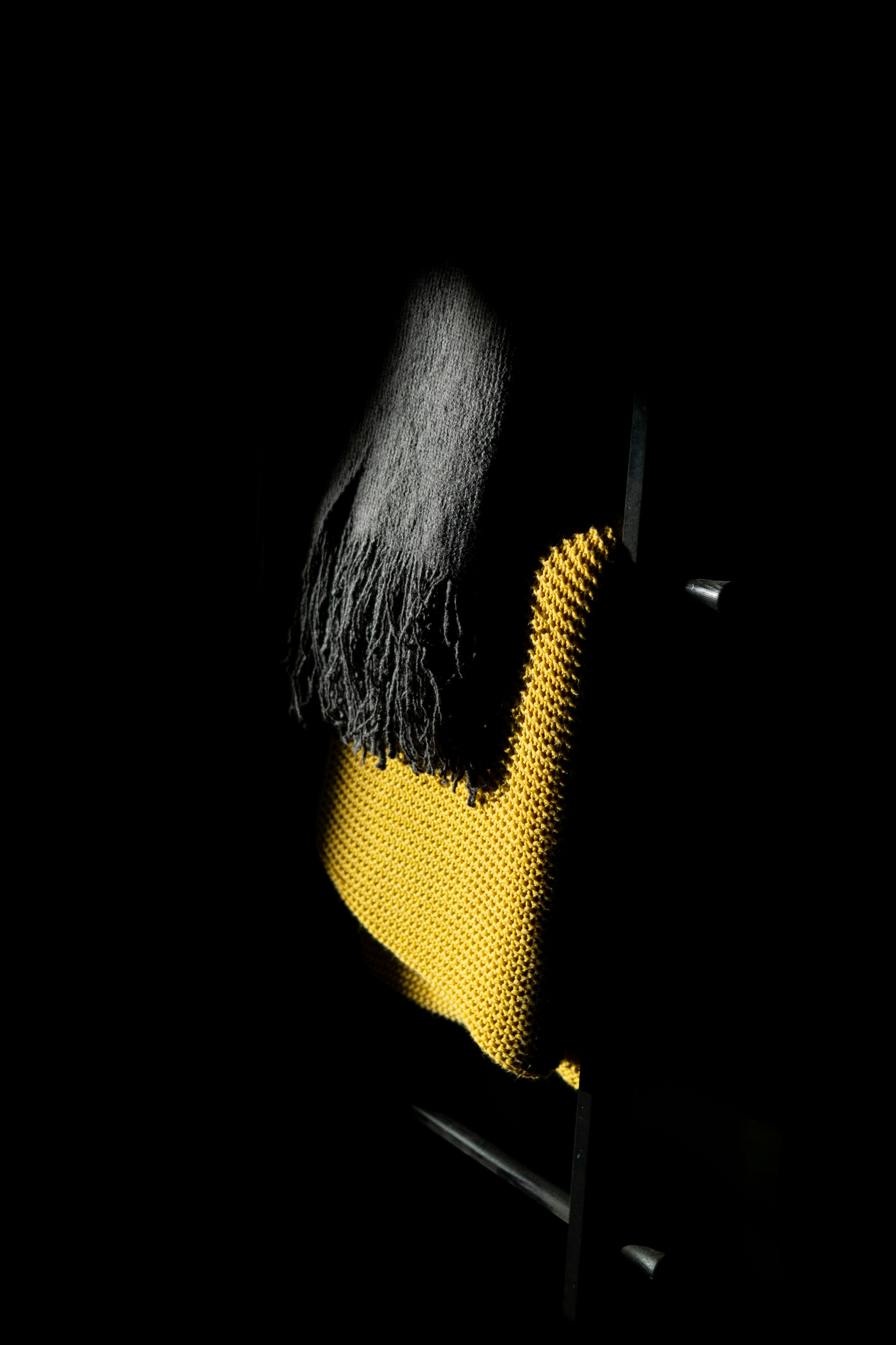 Yellow knitted fabric with fringe inky black background