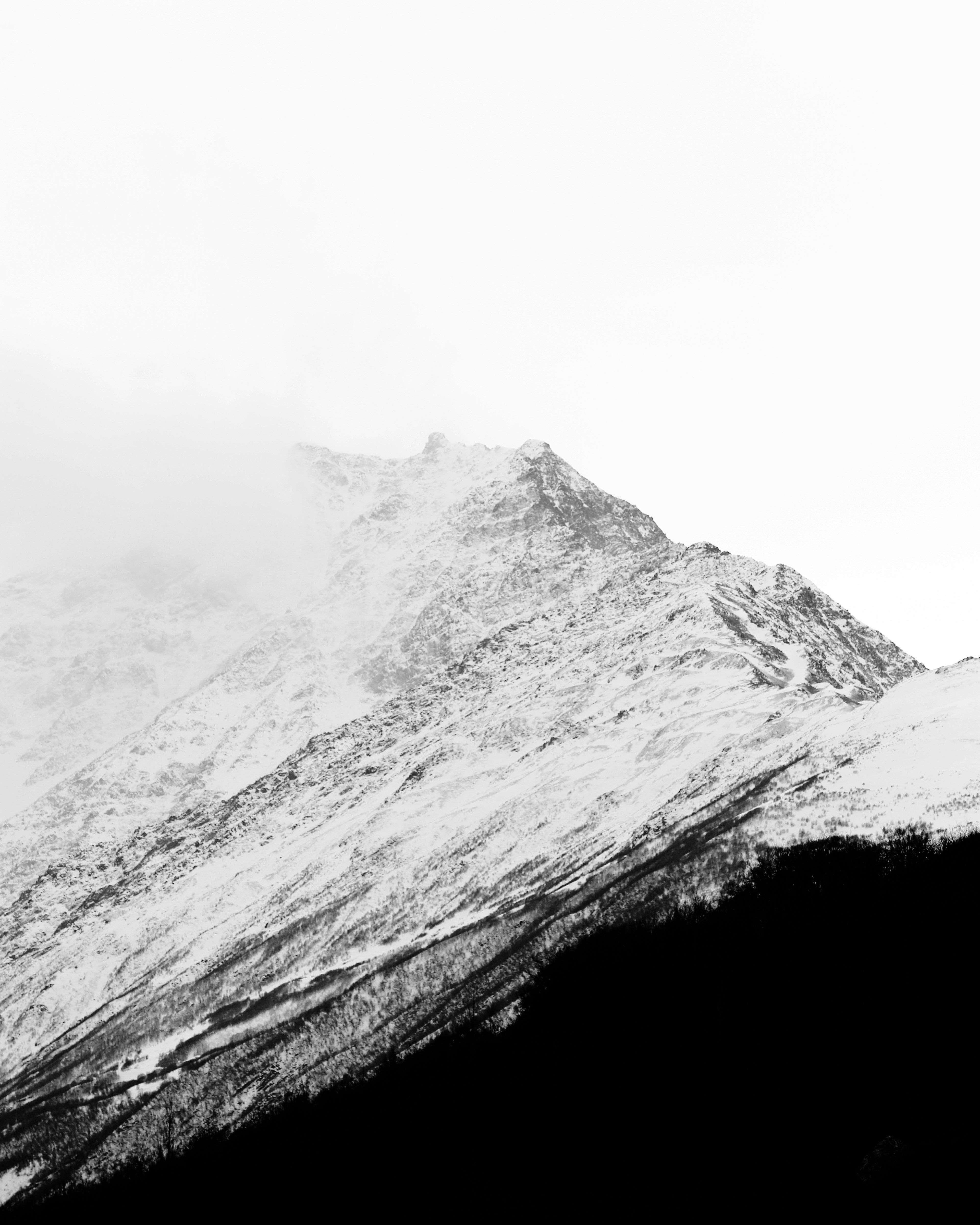 Snow-covered mountain peak shrouded in mist.