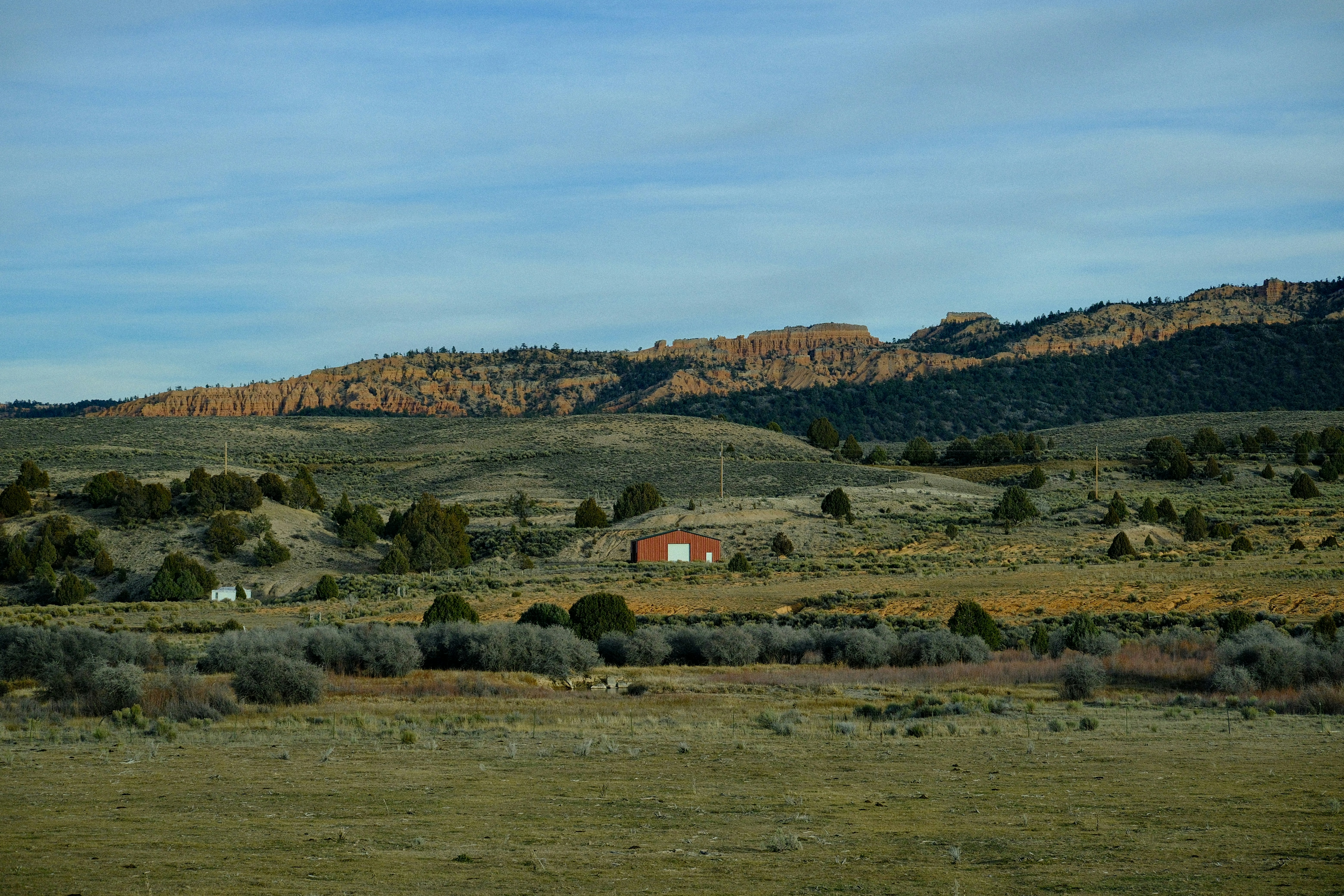 A red barn sits in a vast, arid landscape.