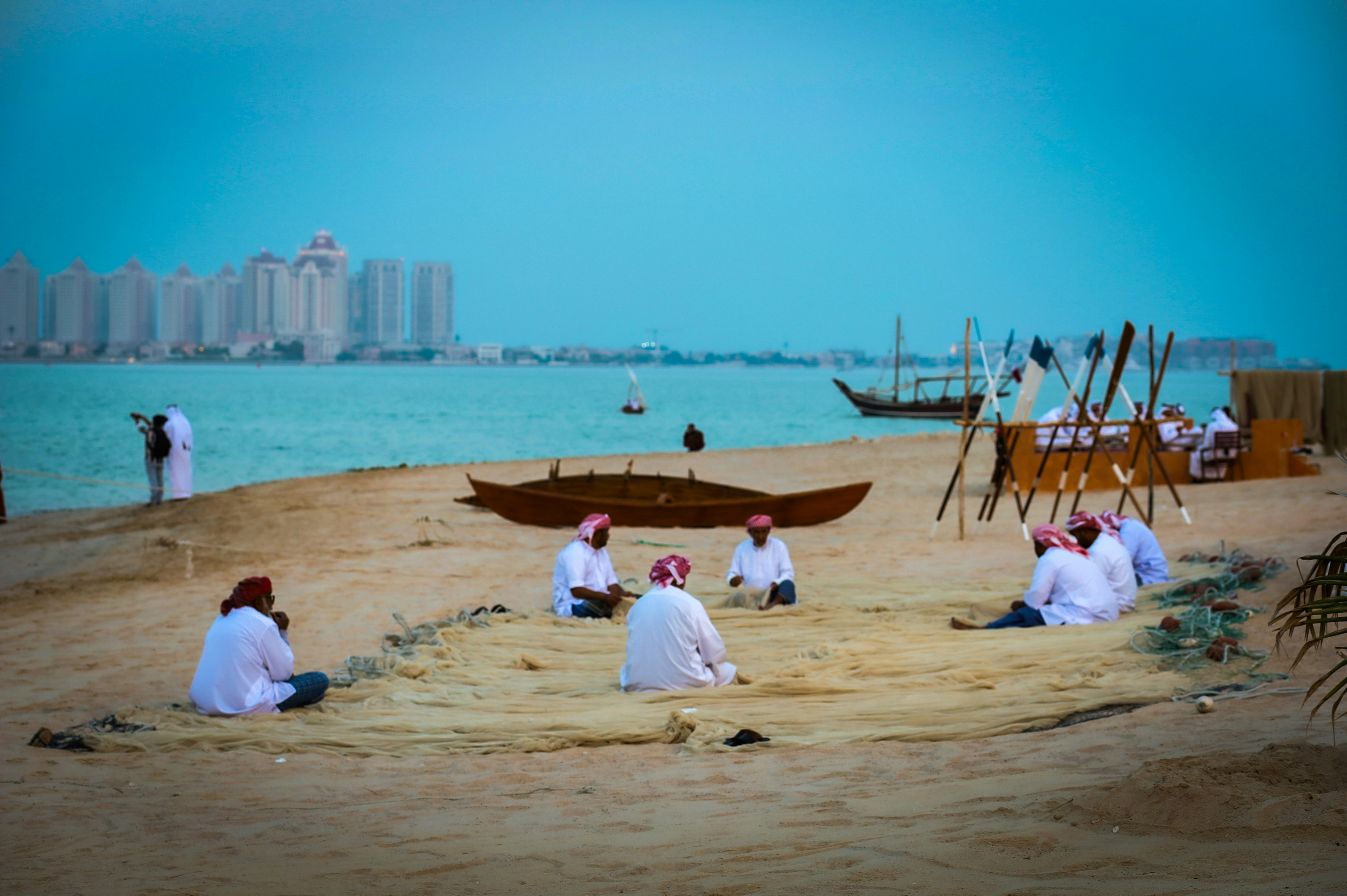 Men gathered on a sandy beach with fishing nets