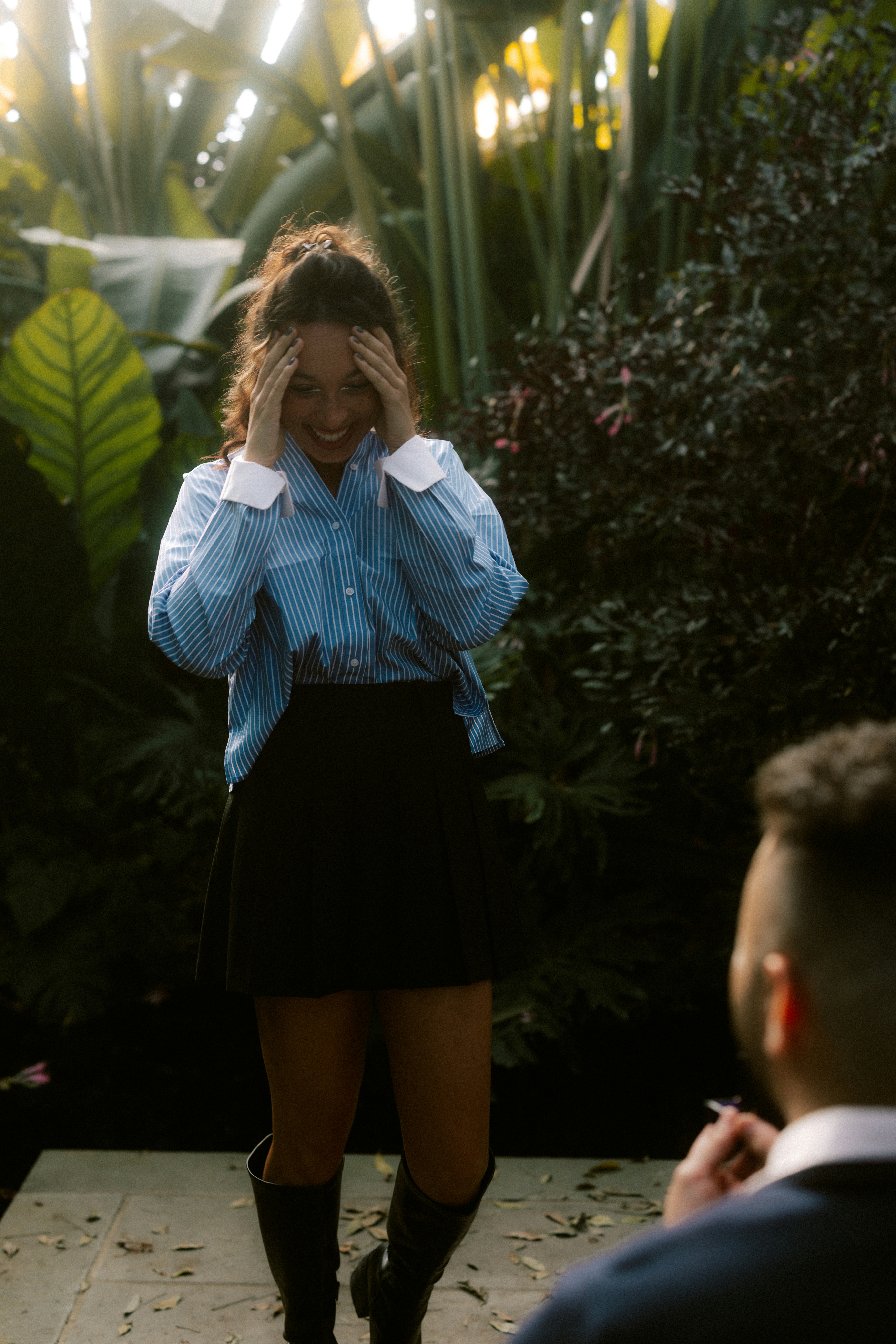A woman laughs in a lush garden setting.
