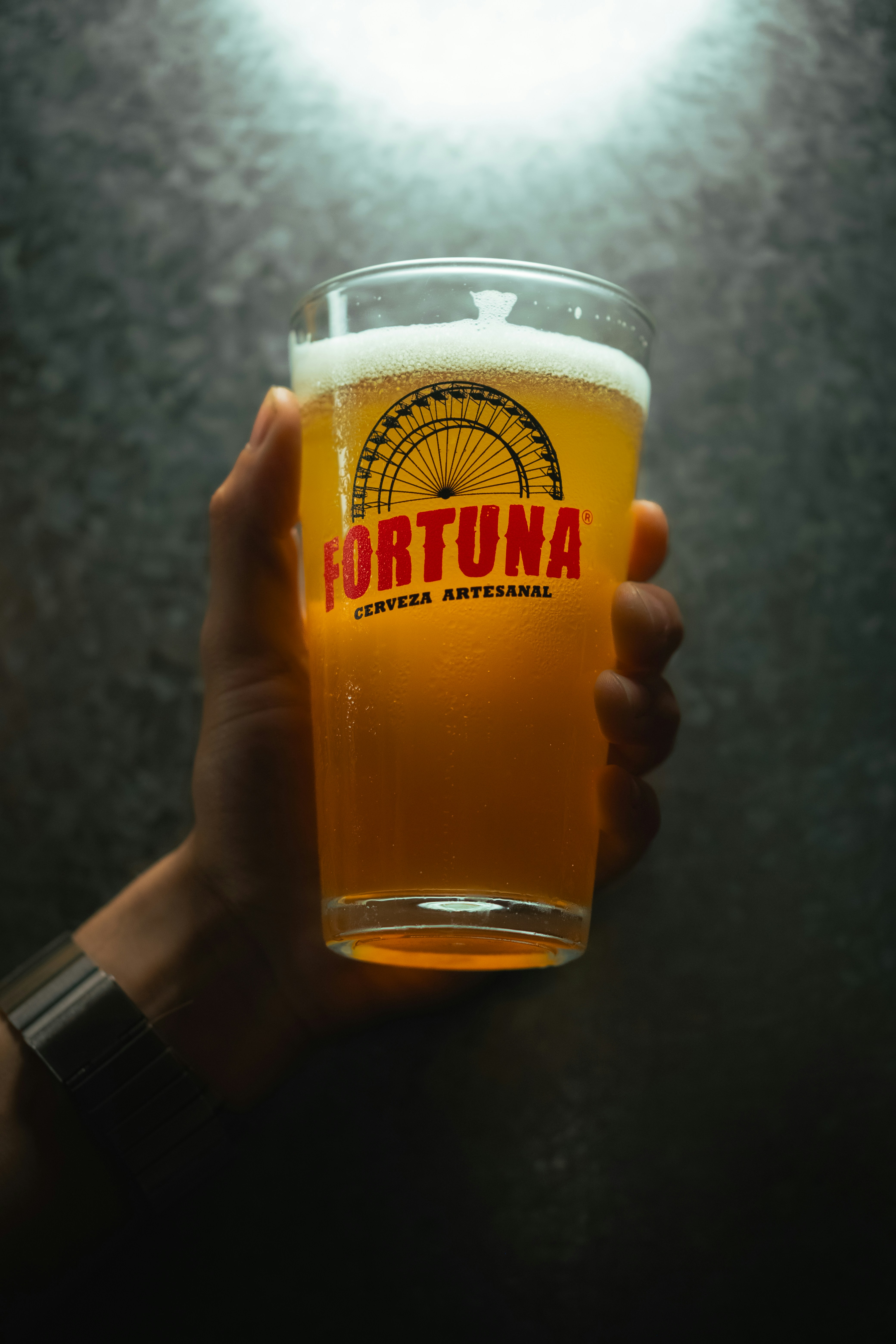 Hand holding a glass of fortuna beer