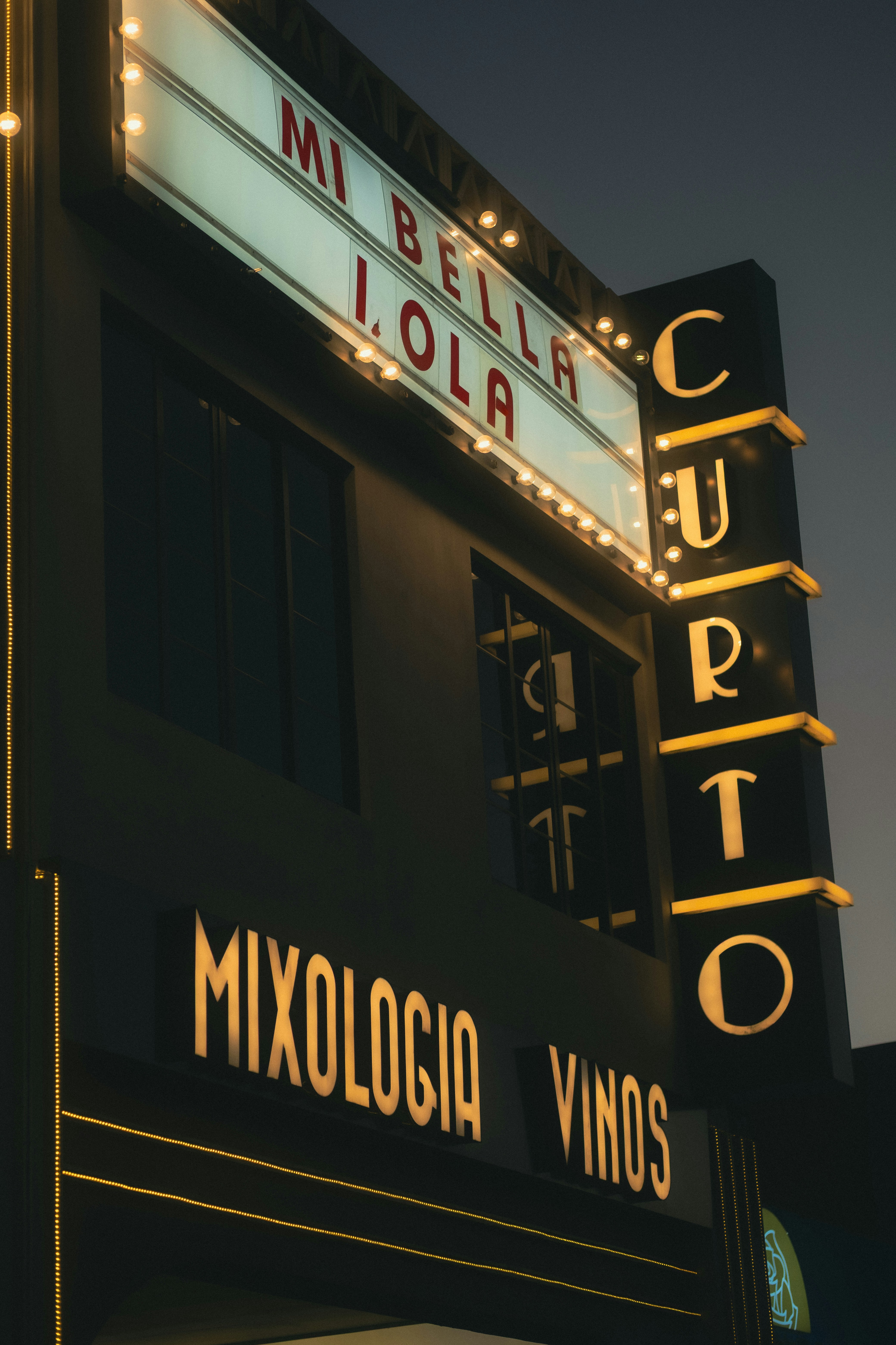 Marquee sign for "mi bella lola" bar at dusk