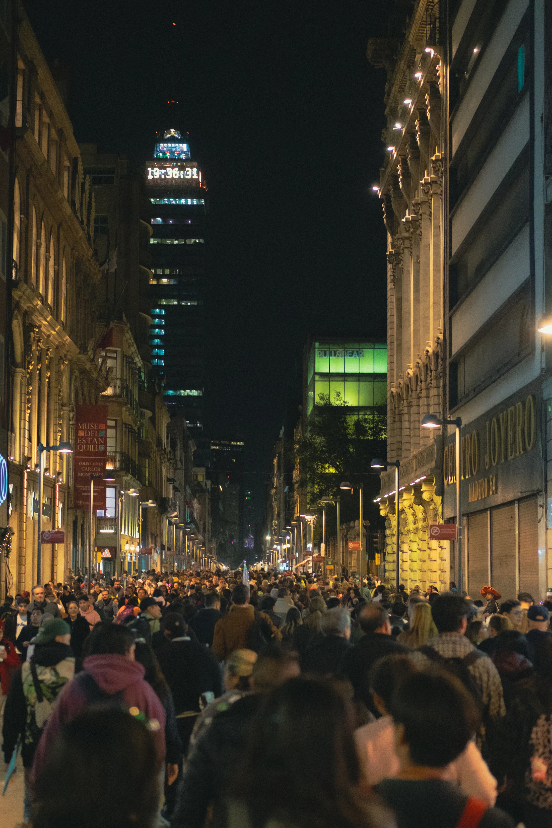 Mexico City street at night, crowded with neon signs and locals