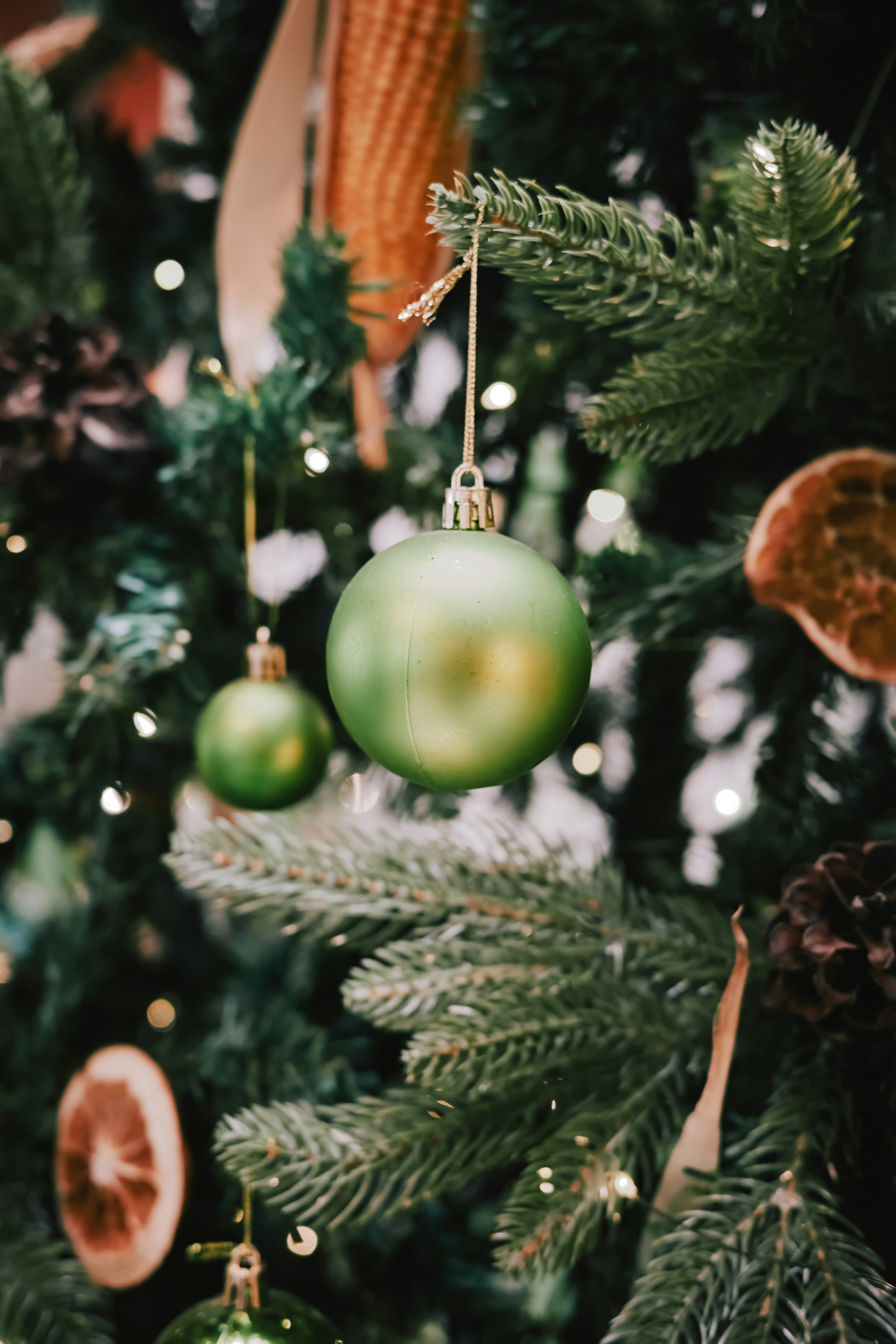 Green ornaments on a decorated christmas tree