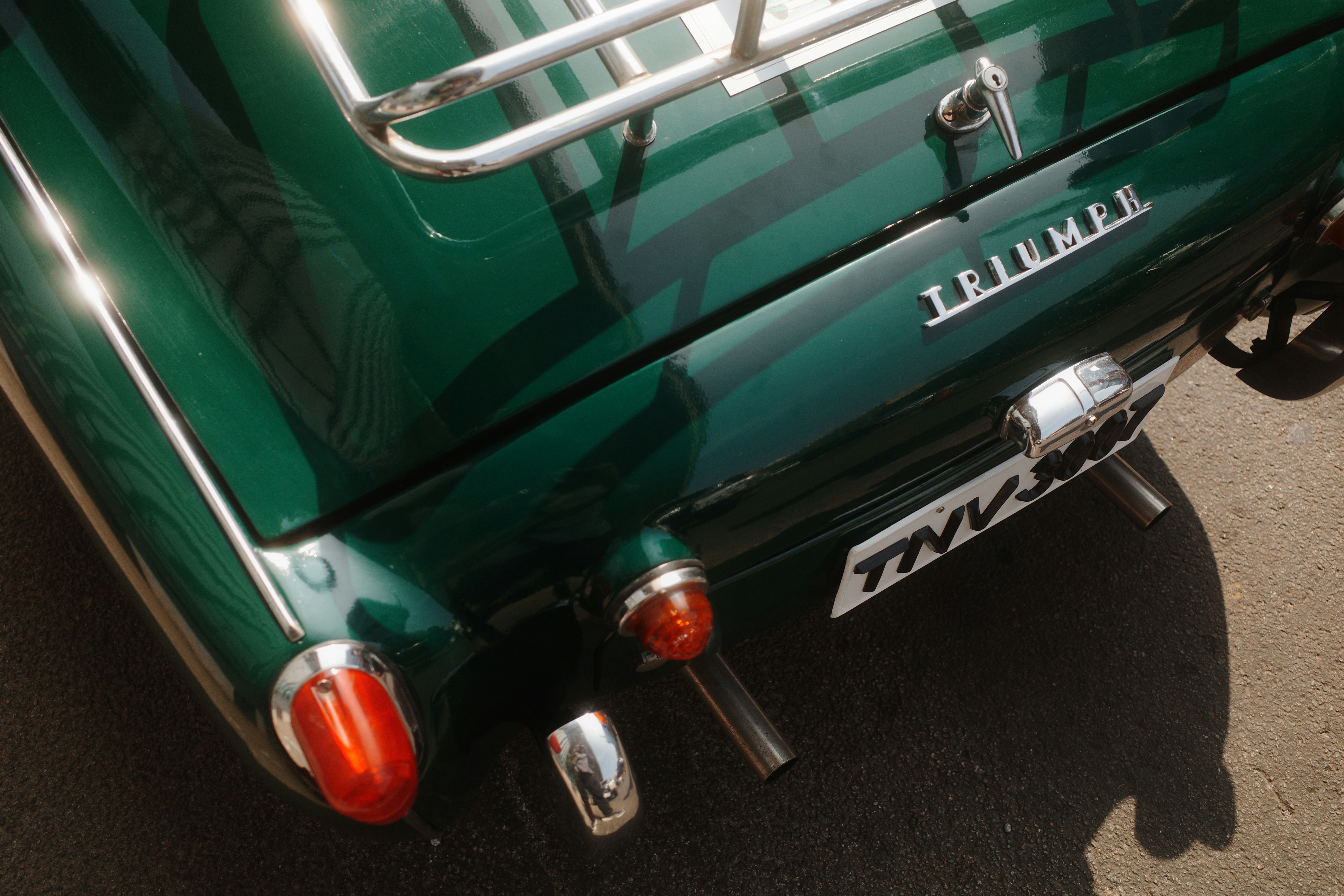 Close-up of a vintage green triumph car's rear.