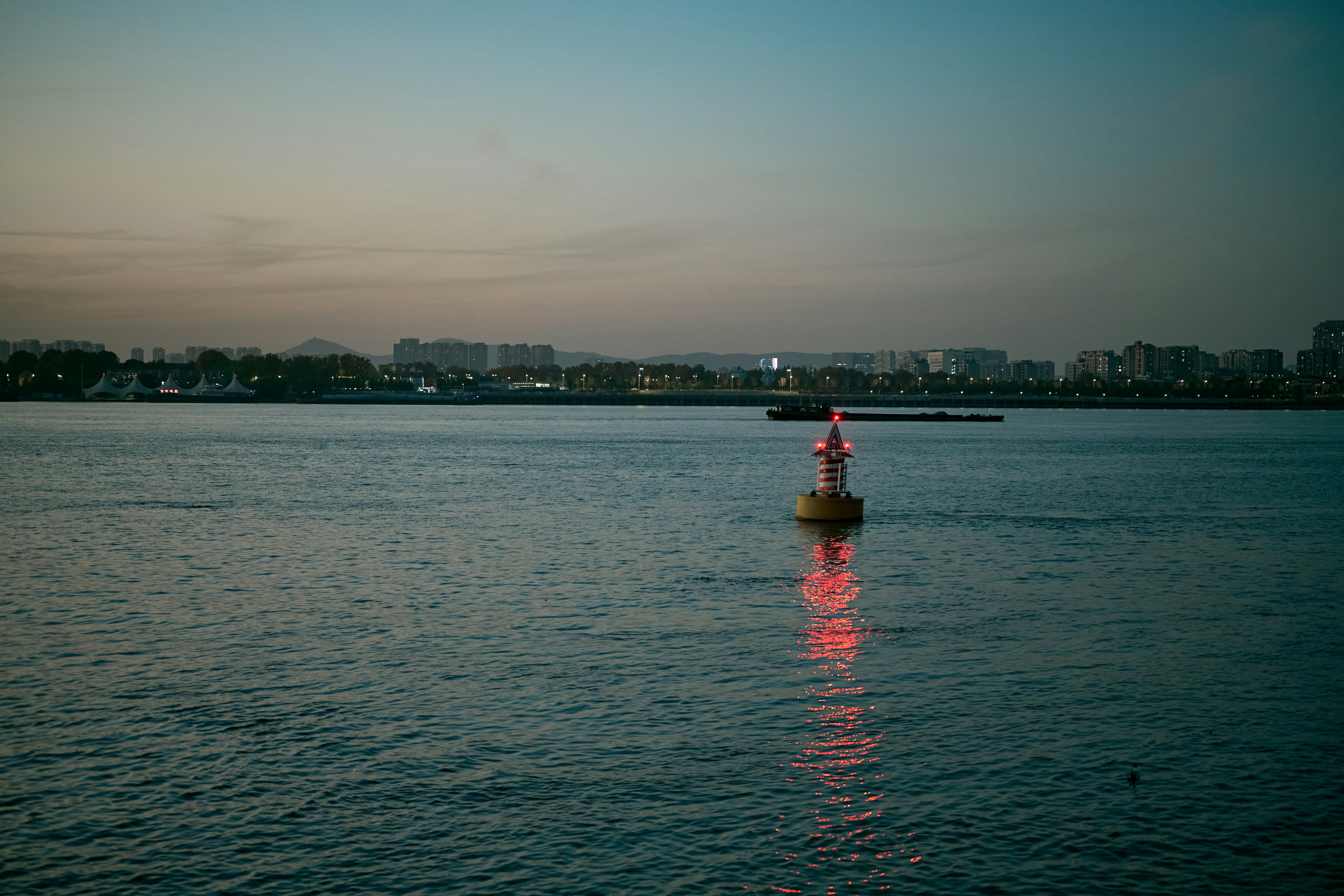 A lighthouse stands in the water at dusk.
