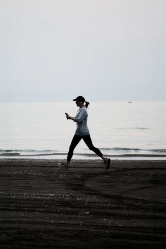 Woman jogging on a dark beach near the ocean