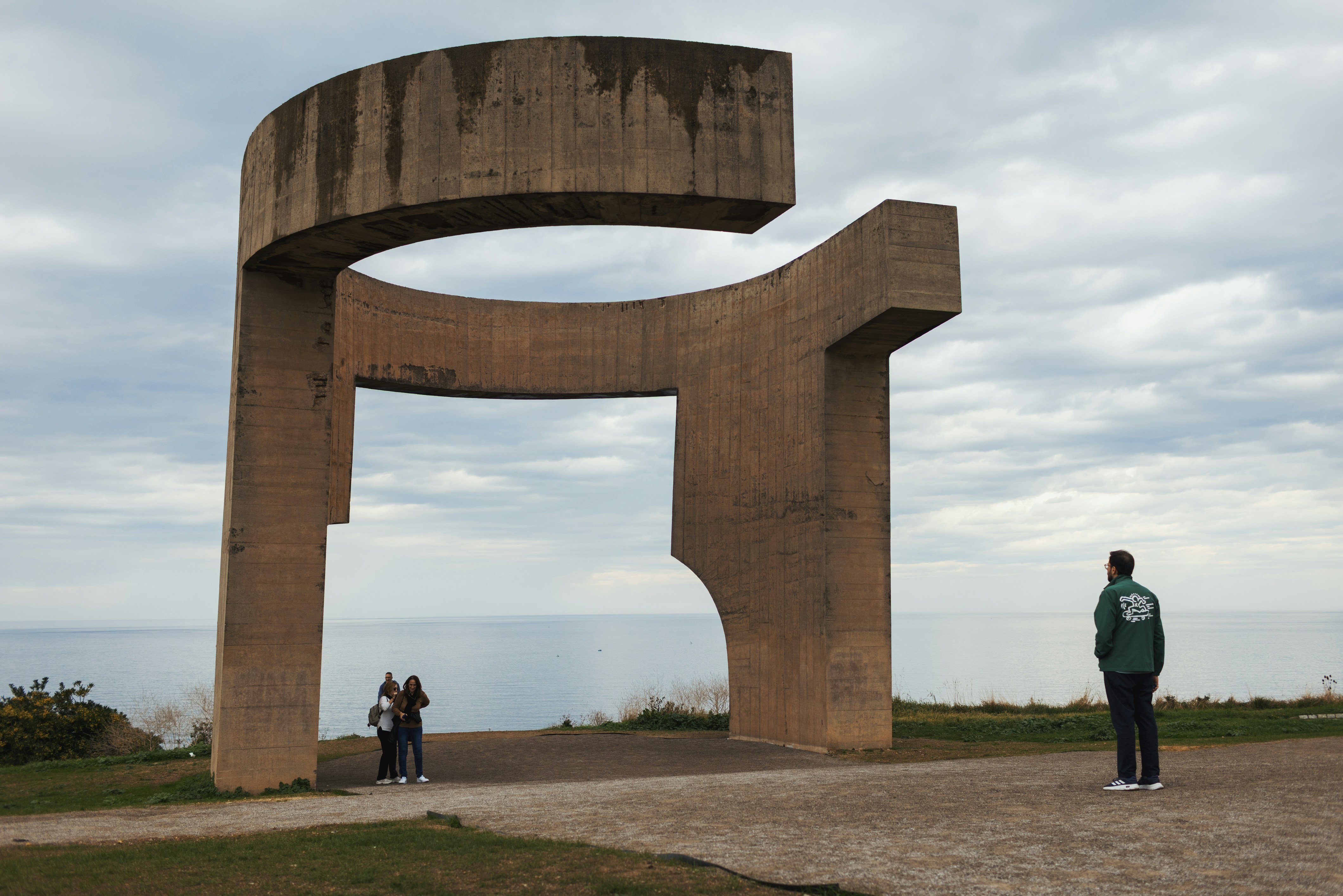 Concrete sculpture overlooking the ocean with people