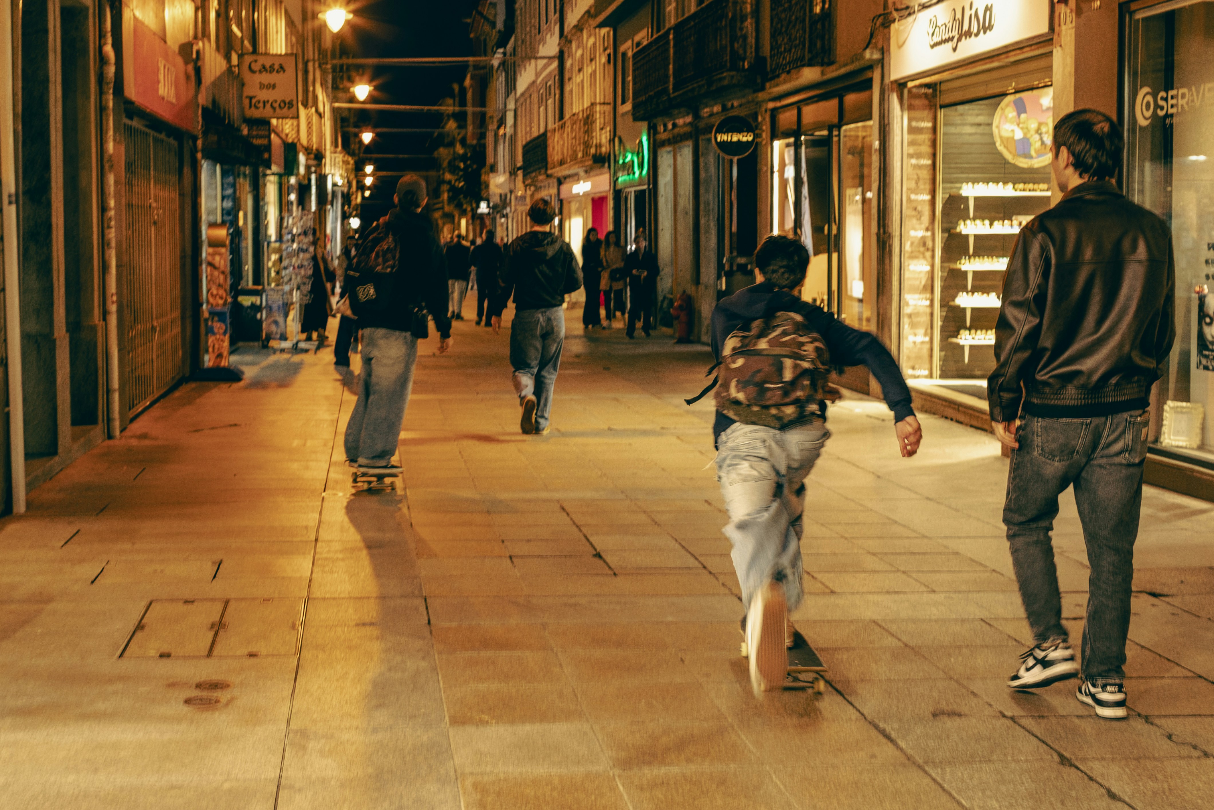 Young people skateboarding down a city street at night