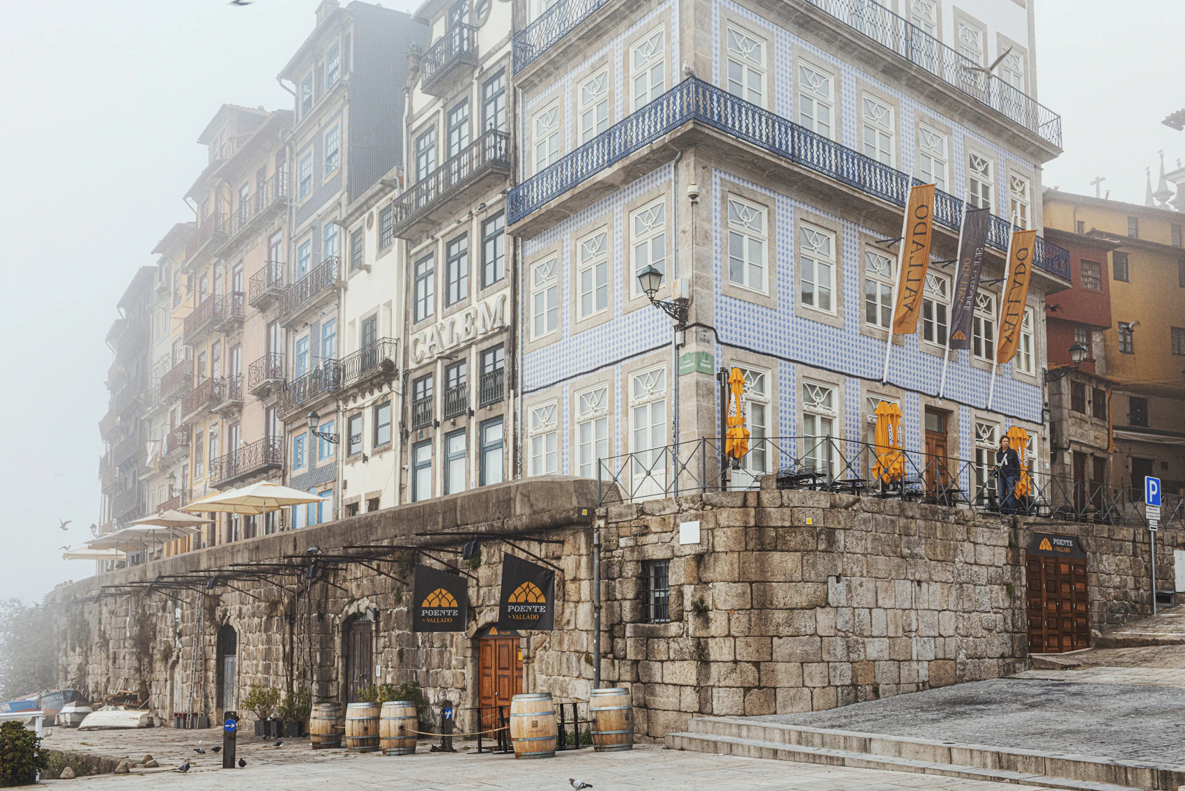 Blue and white tiled buildings rising from Porto's riverfront in soft fog
