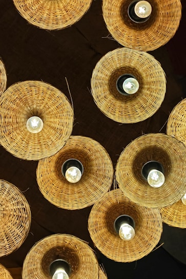 Woven bamboo lamps hanging from a dark ceiling