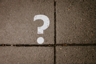 White question mark painted on concrete pavement