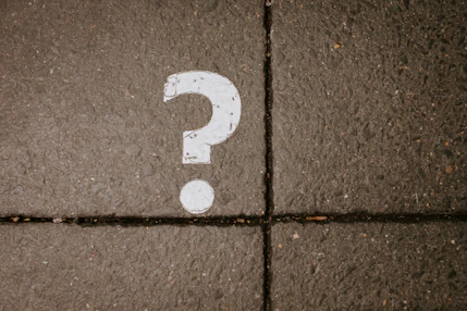 White question mark painted on concrete pavement