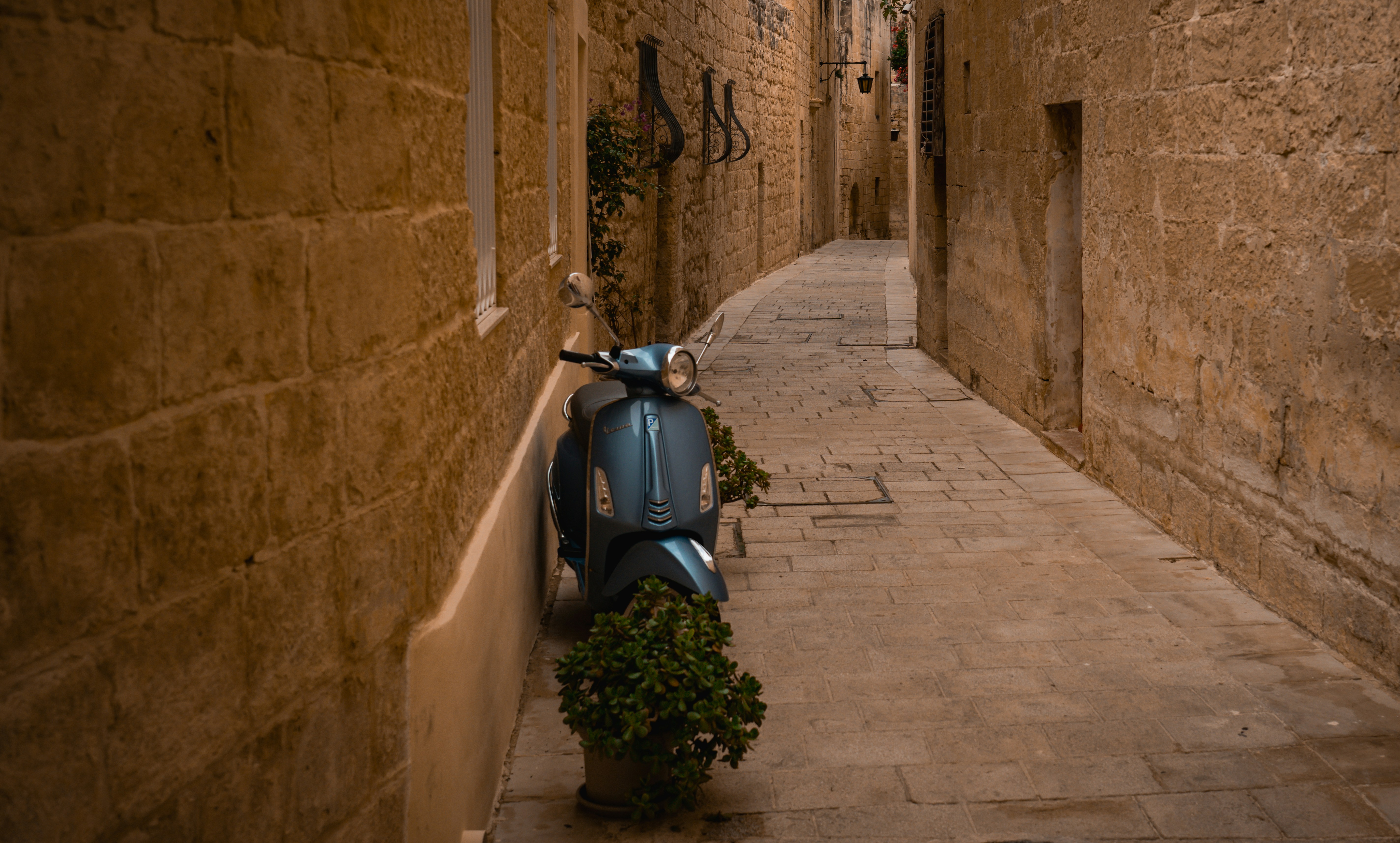 Scooter parked on a narrow cobblestone alleyway.