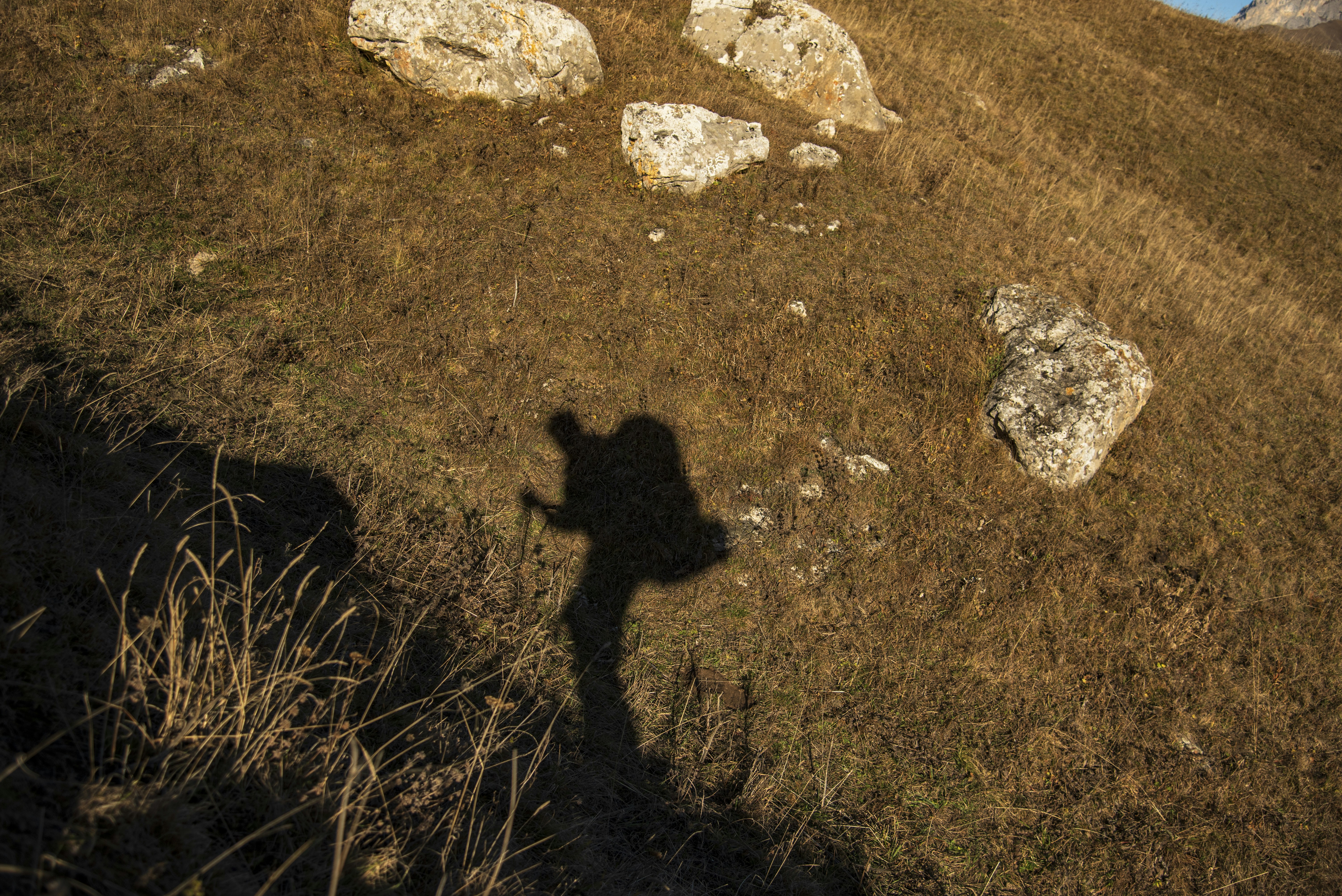 Shadow of a hiker with backpack on grassy slope