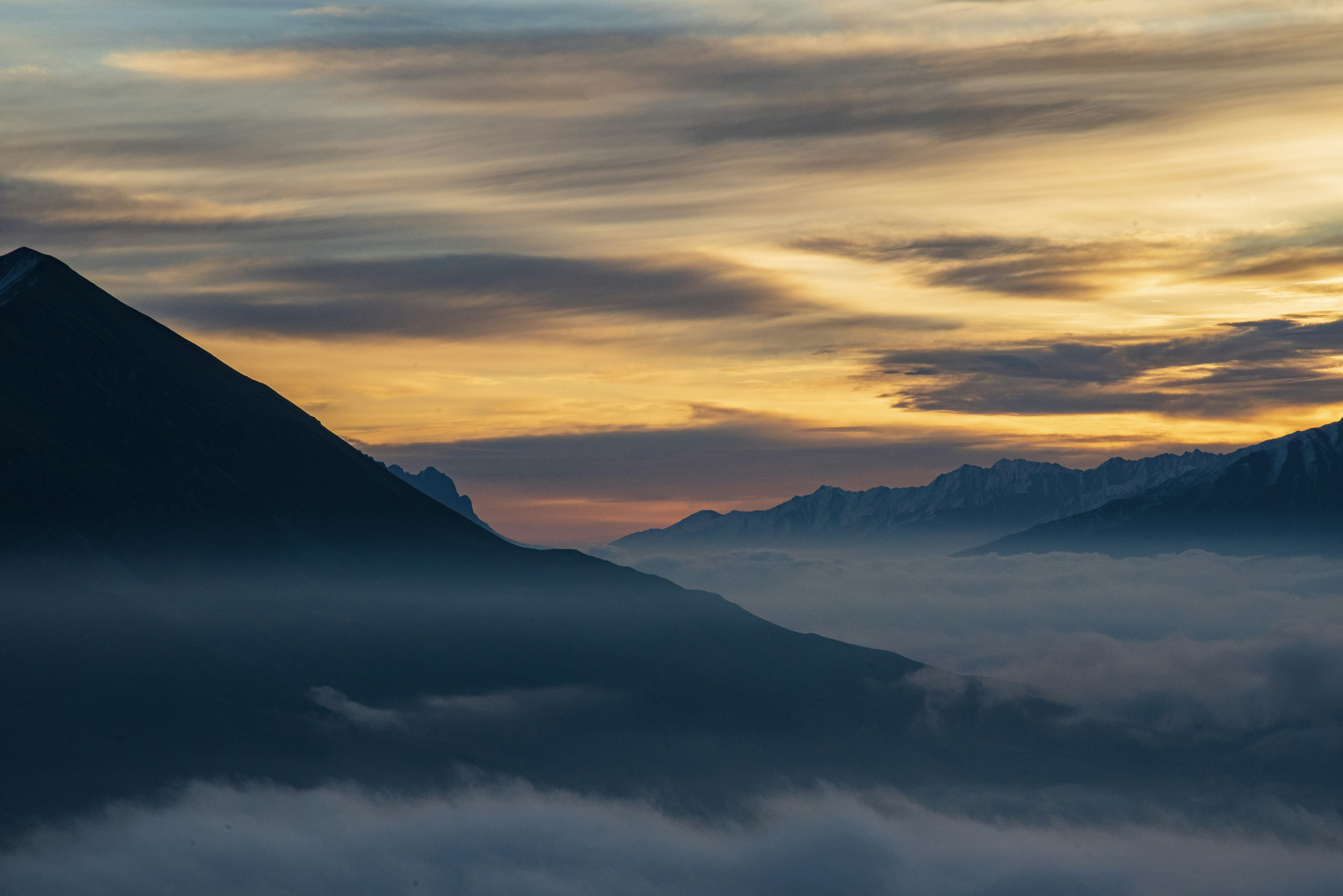 Mountain peaks emerge from a sea of clouds at sunset.