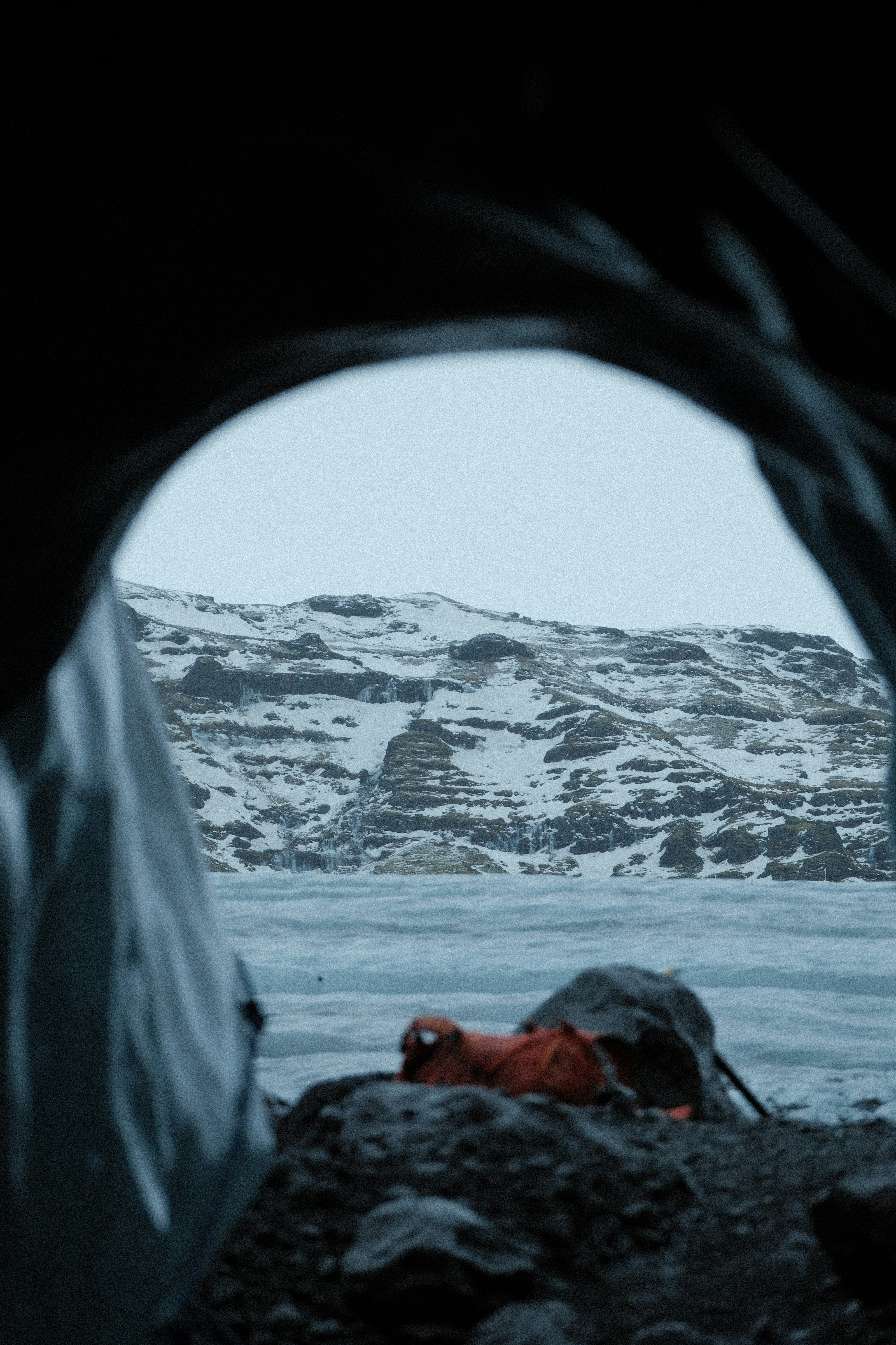 Tent view of a frozen landscape with orange sleeping bag.