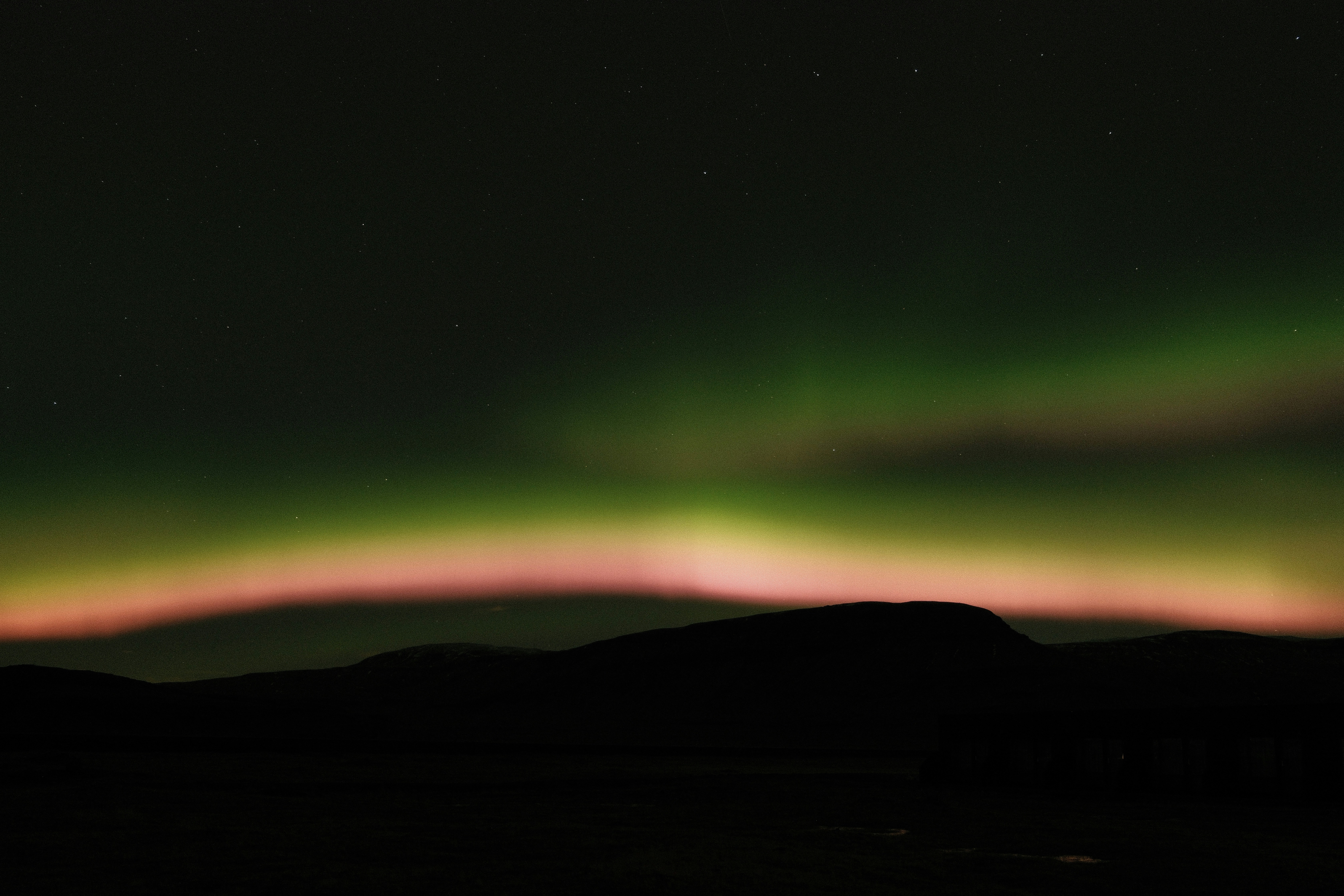Aurora borealis glows over silhouetted hills