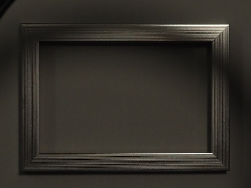 Empty metallic picture frame on a dark wall