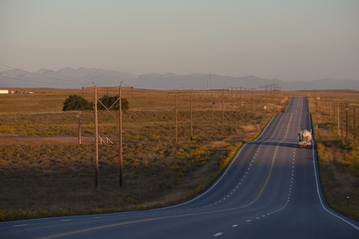 Long empty road stretching towards distant mountains at sunset