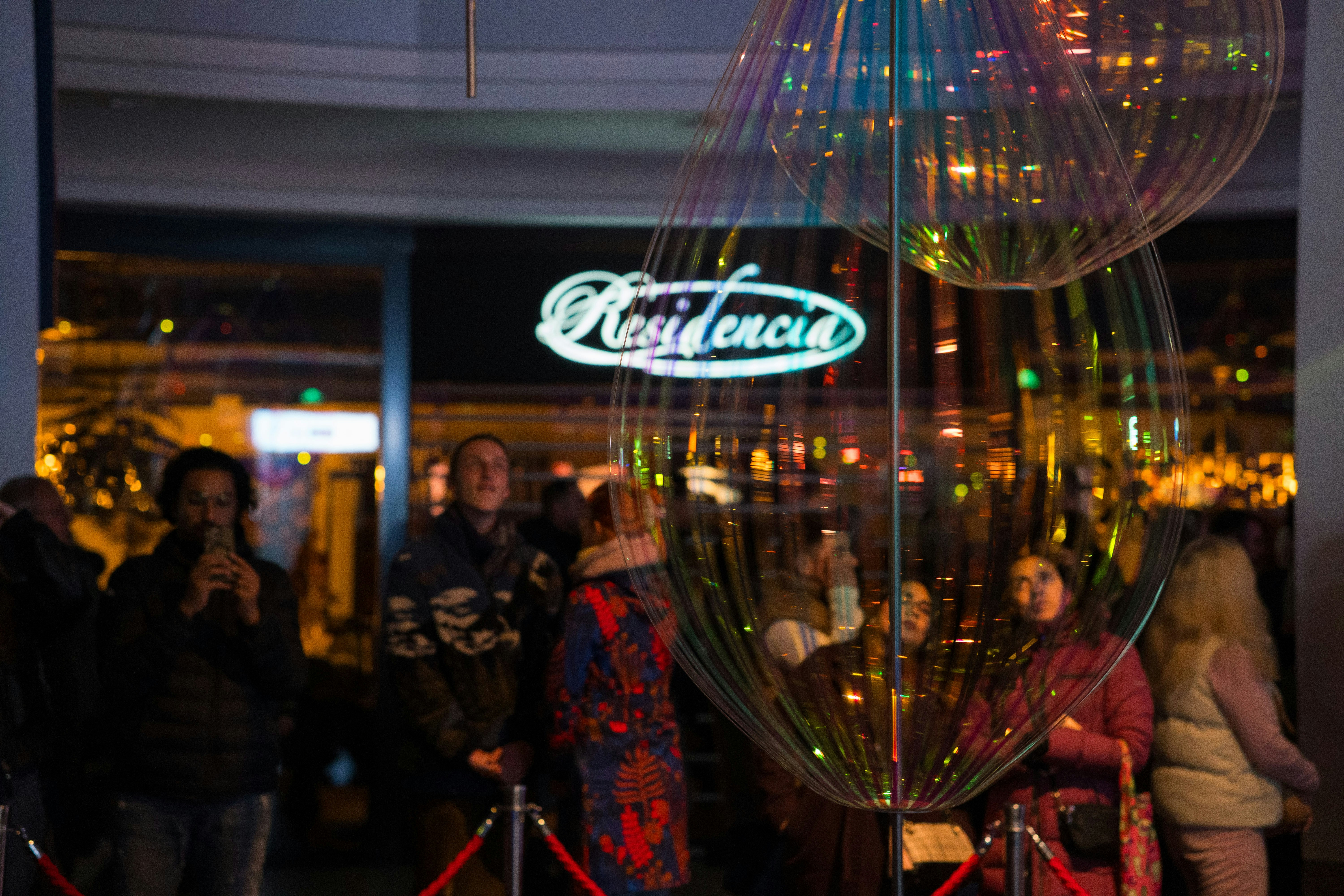 People gathered outside a brightly lit establishment at night.