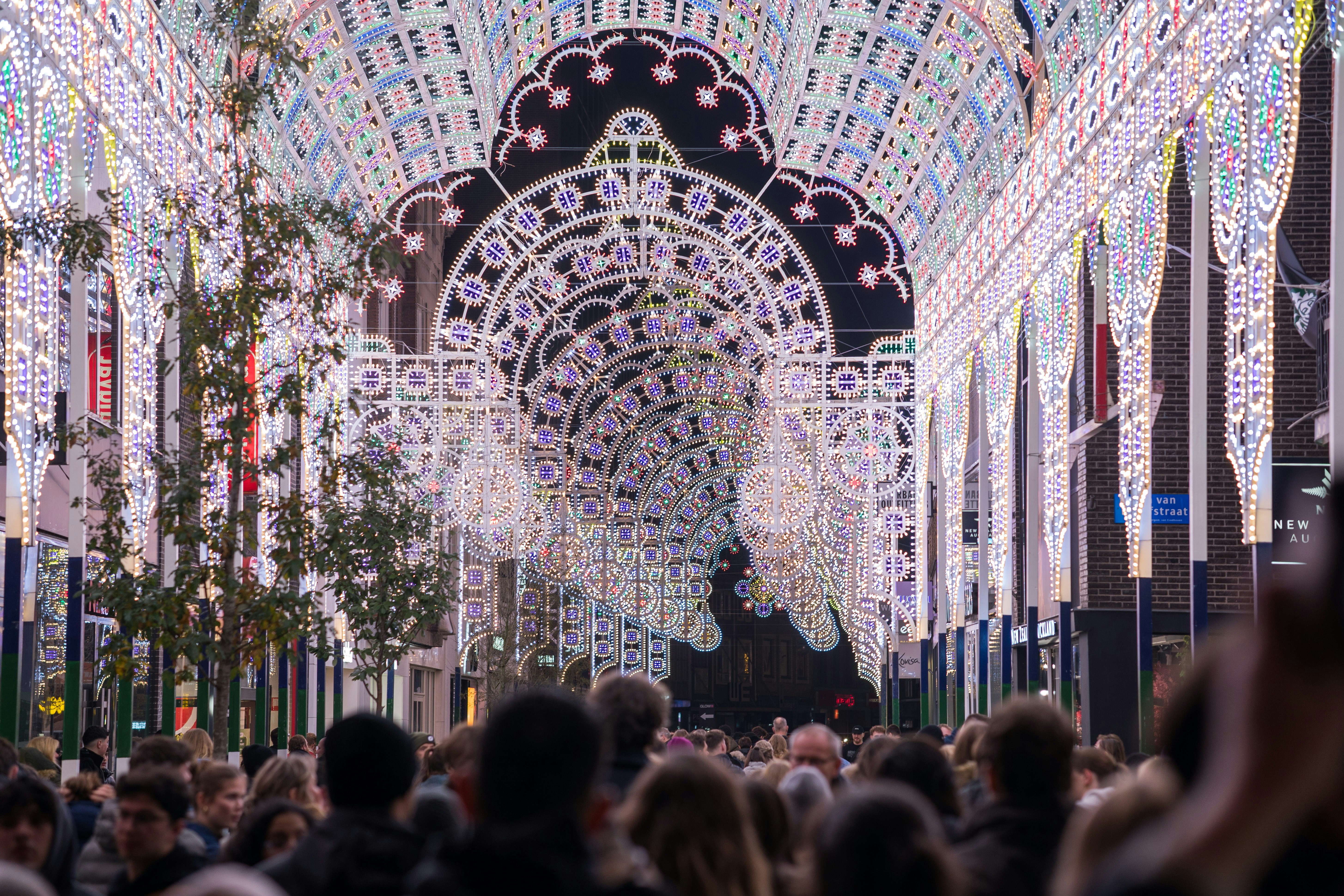 Crowd walking through a street illuminated by festive lights