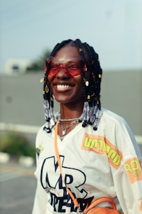 A woman with braided hair wearing sunglasses and a jersey.