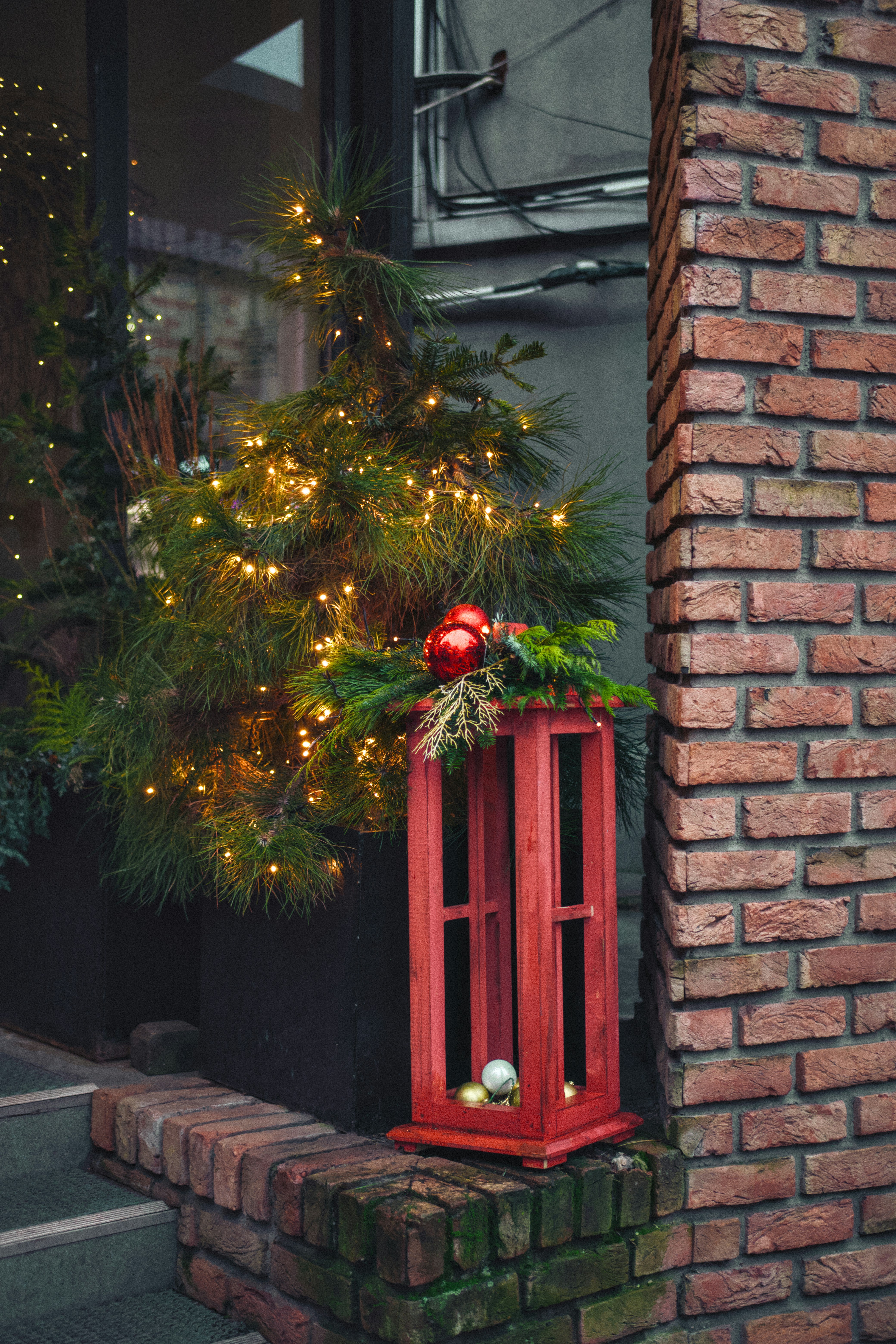 Decorated christmas tree with red lantern and brick wall