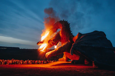 Dragon sculpture breathing fire at dusk with crowd