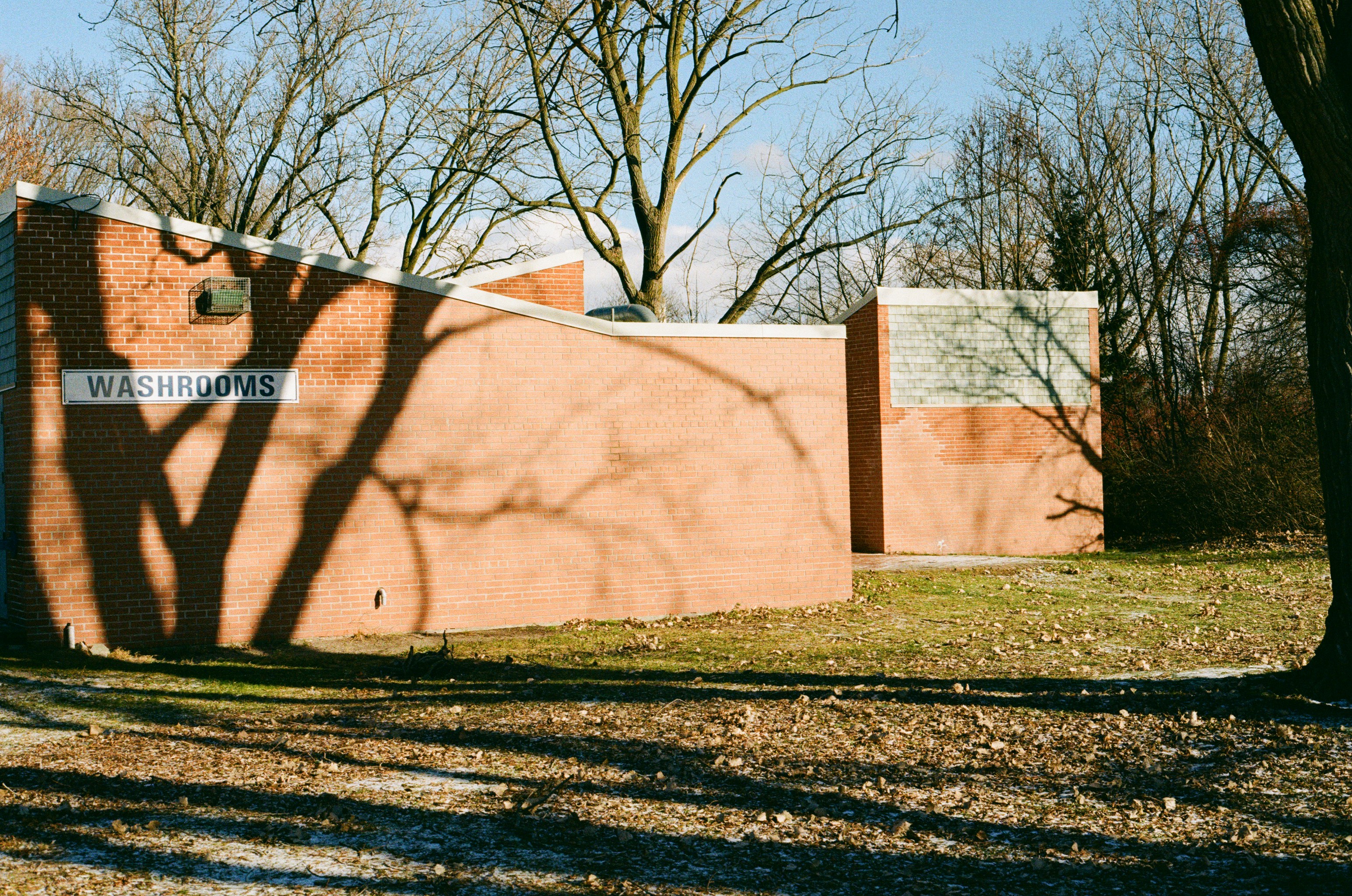 A closed park washroom building with a portable washroom unit beside it in an Ontario park in autumn.