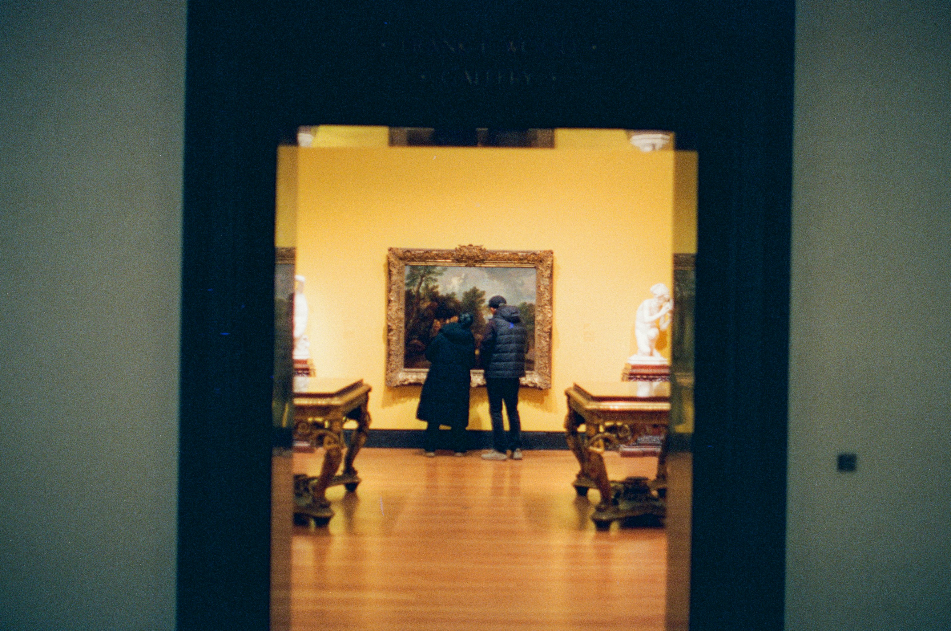 Two people admire painting in a museum gallery.