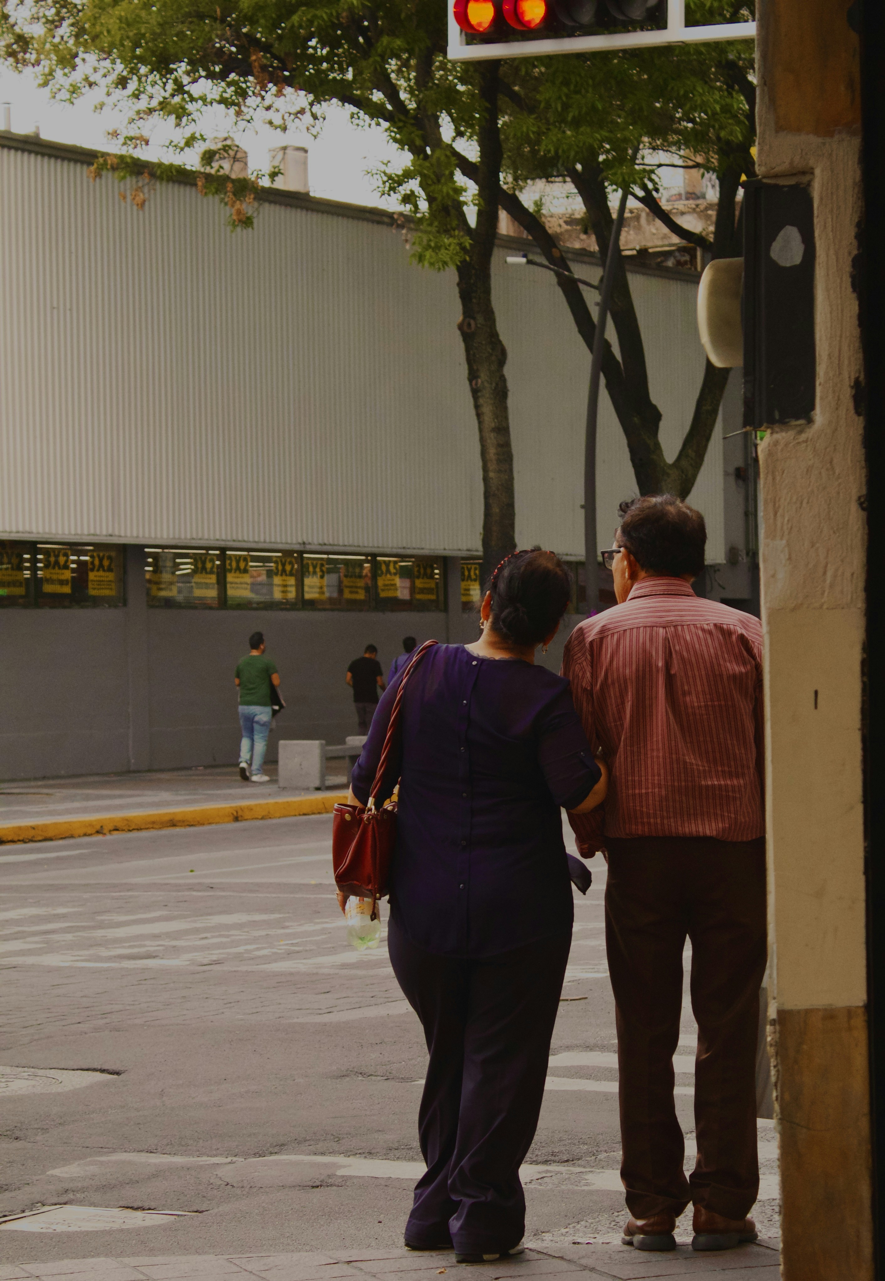 Una pareja cruza una calle cerca del semáforo.