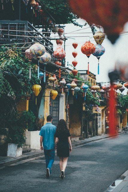 Couple walking down a street decorated with lanterns.