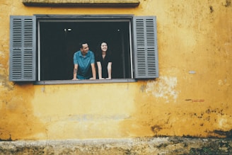 Couple looking out of a yellow window