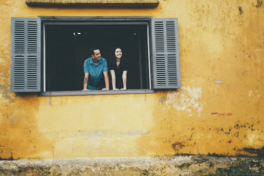 Couple looking out of a yellow window