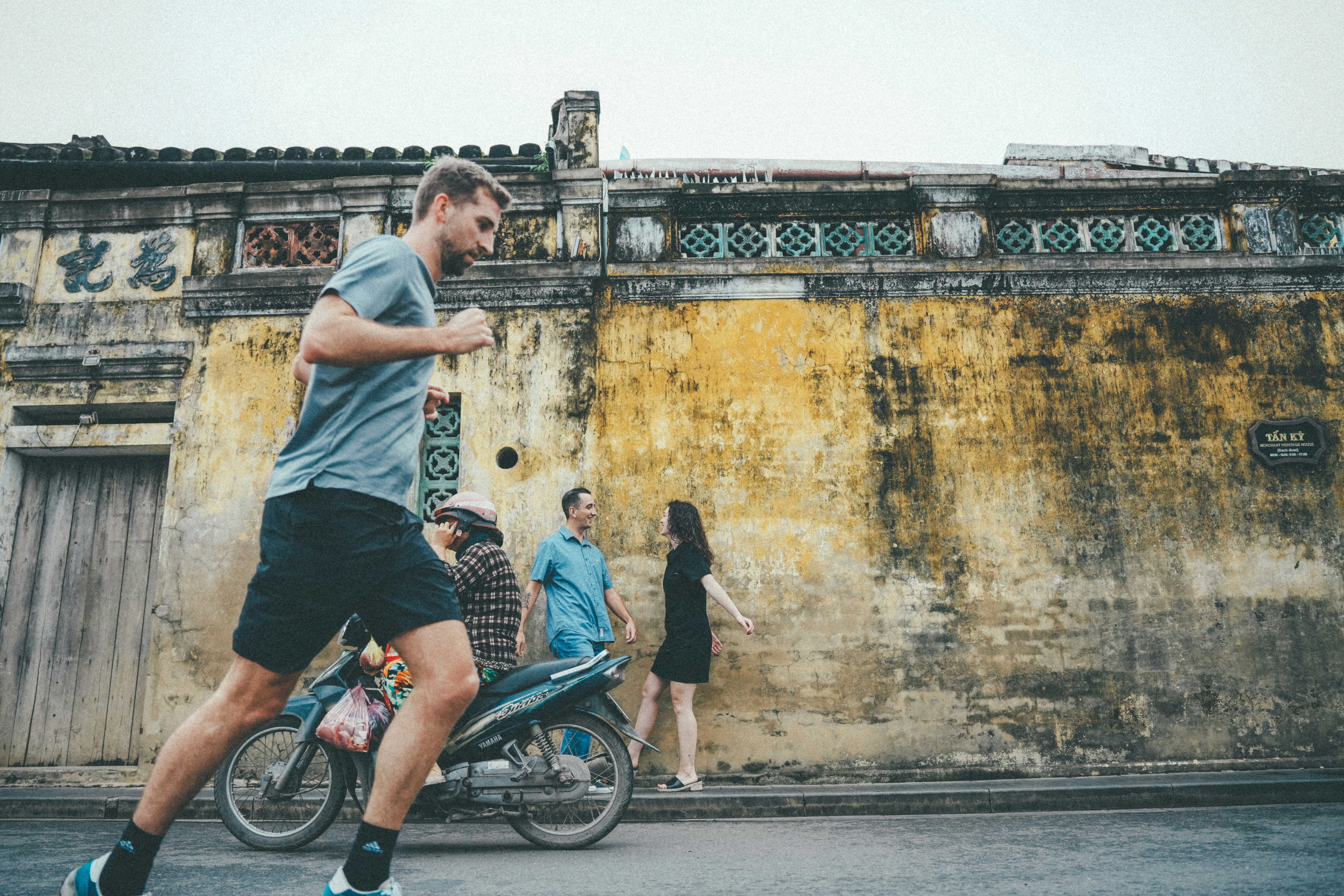 Man running past a motorcycle and people