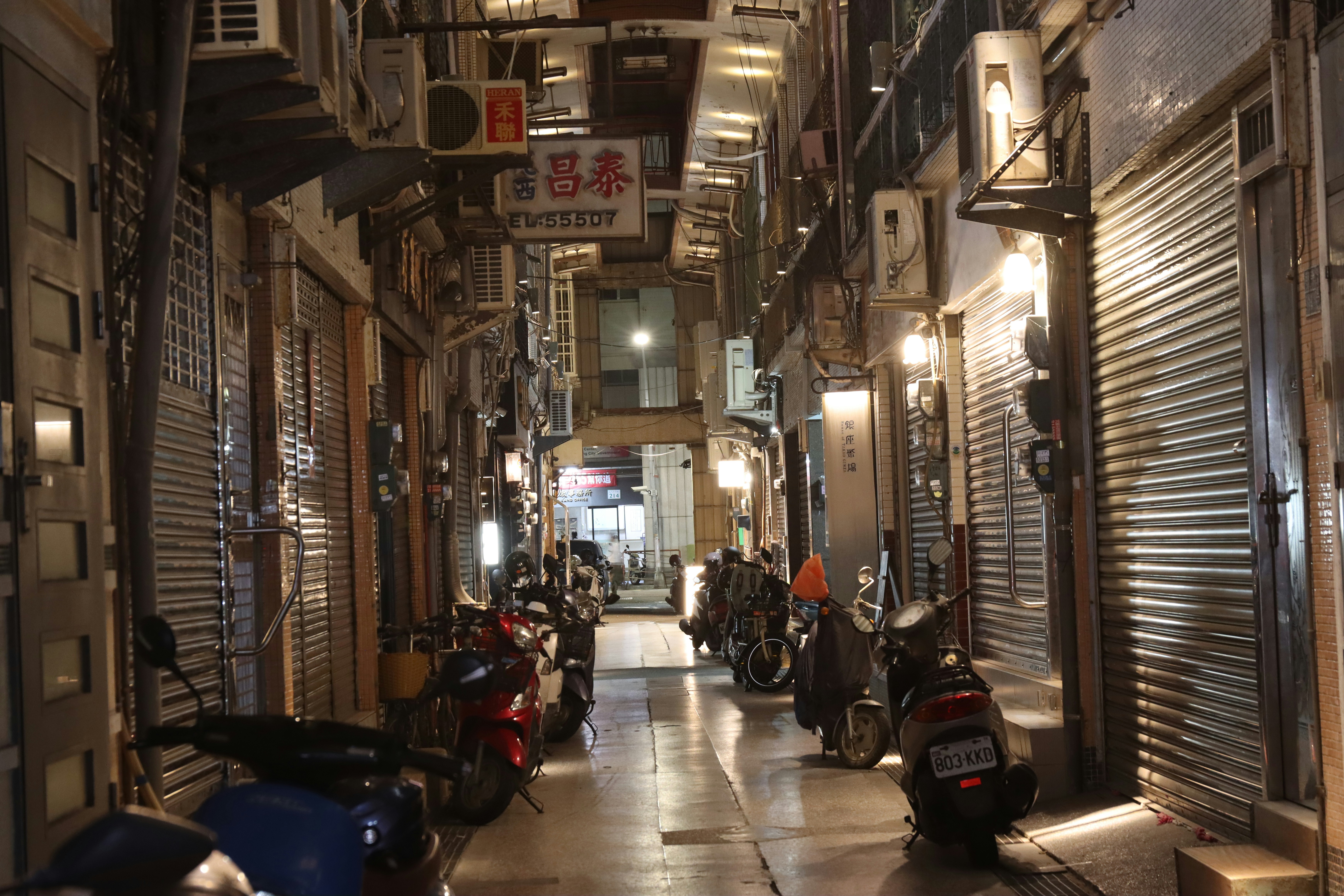 Motorcycles parked in a narrow alleyway at night.