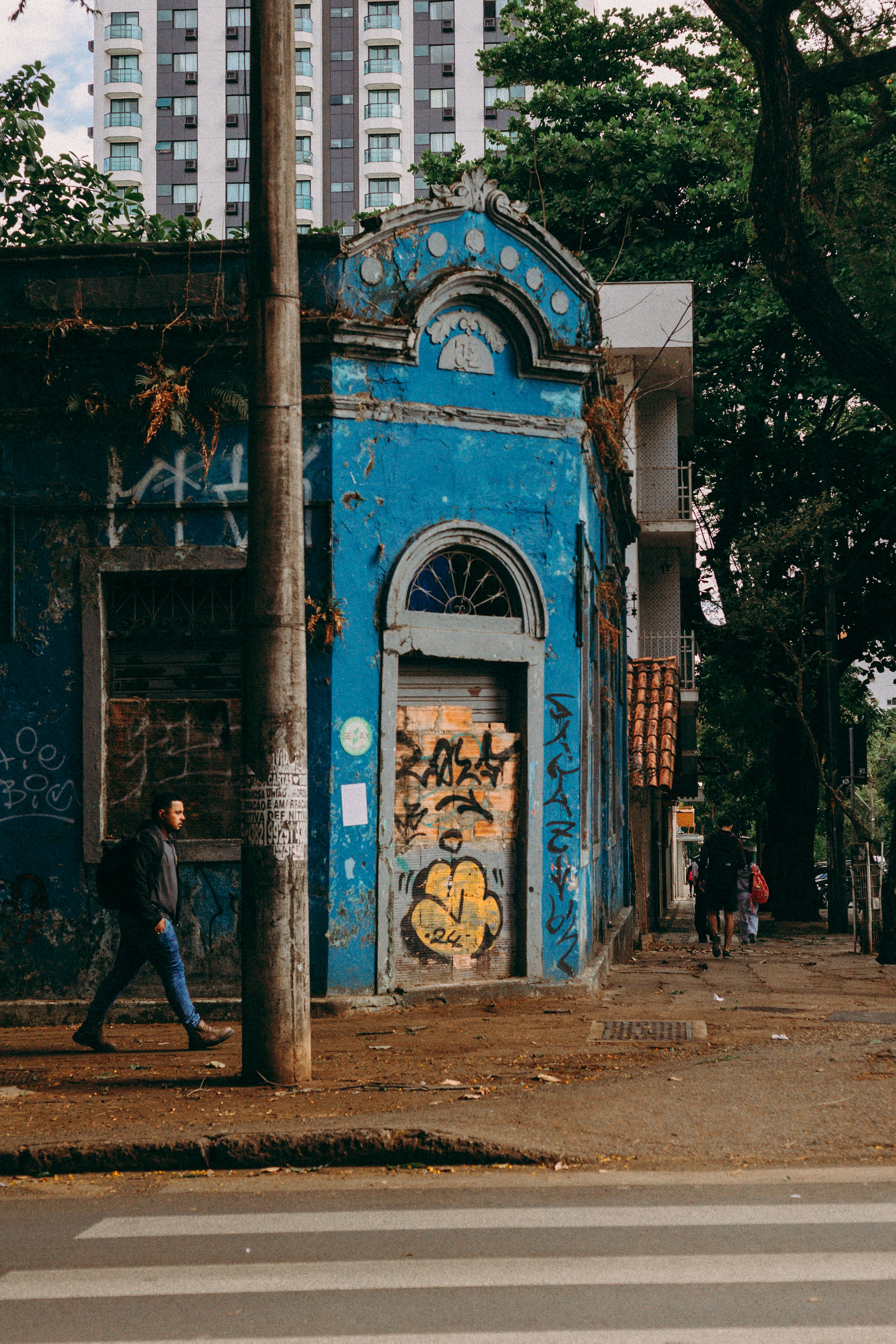 Man walks past a graffiti-covered blue building.