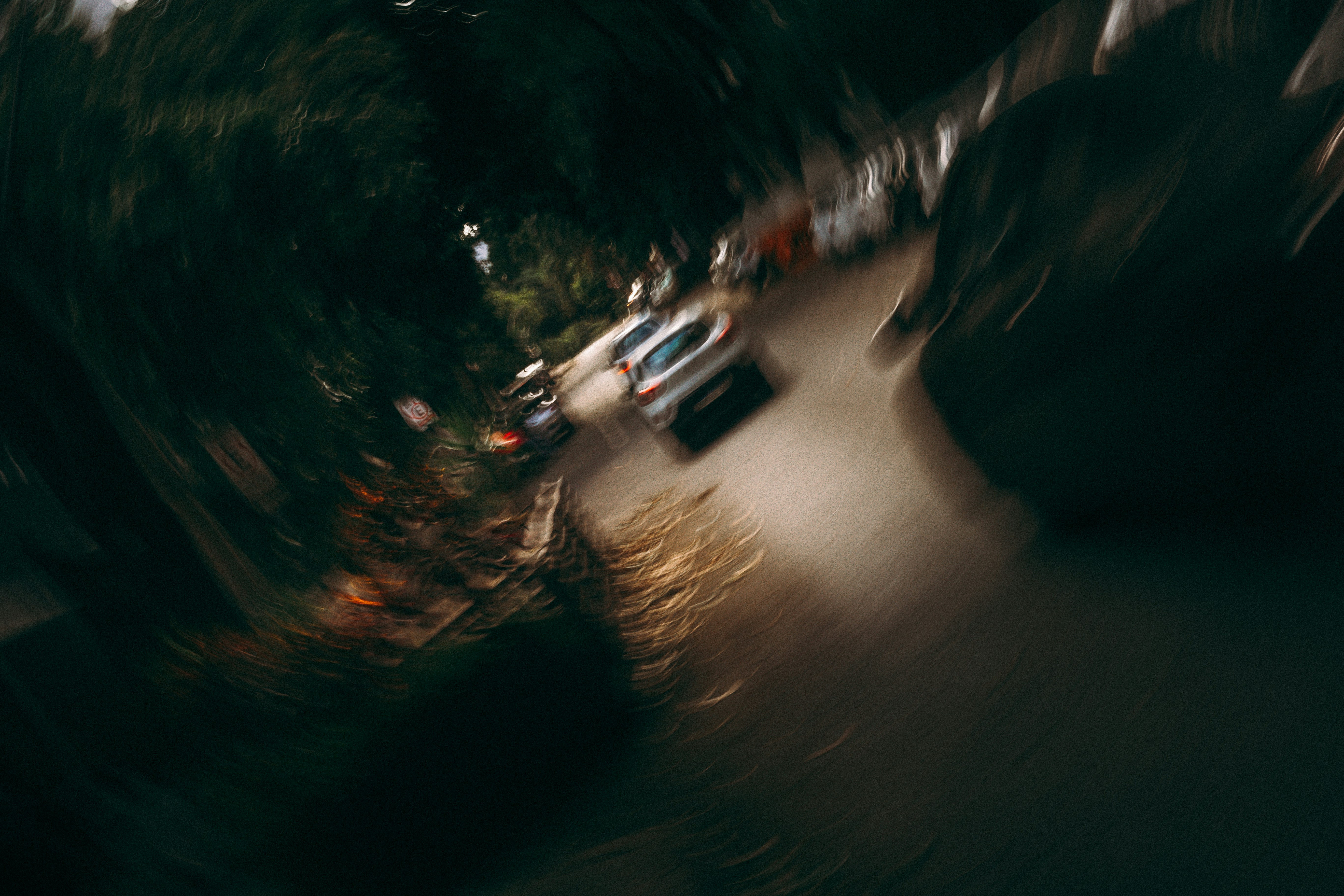 Coche circulando por una calle oscura y arbolada de noche.
