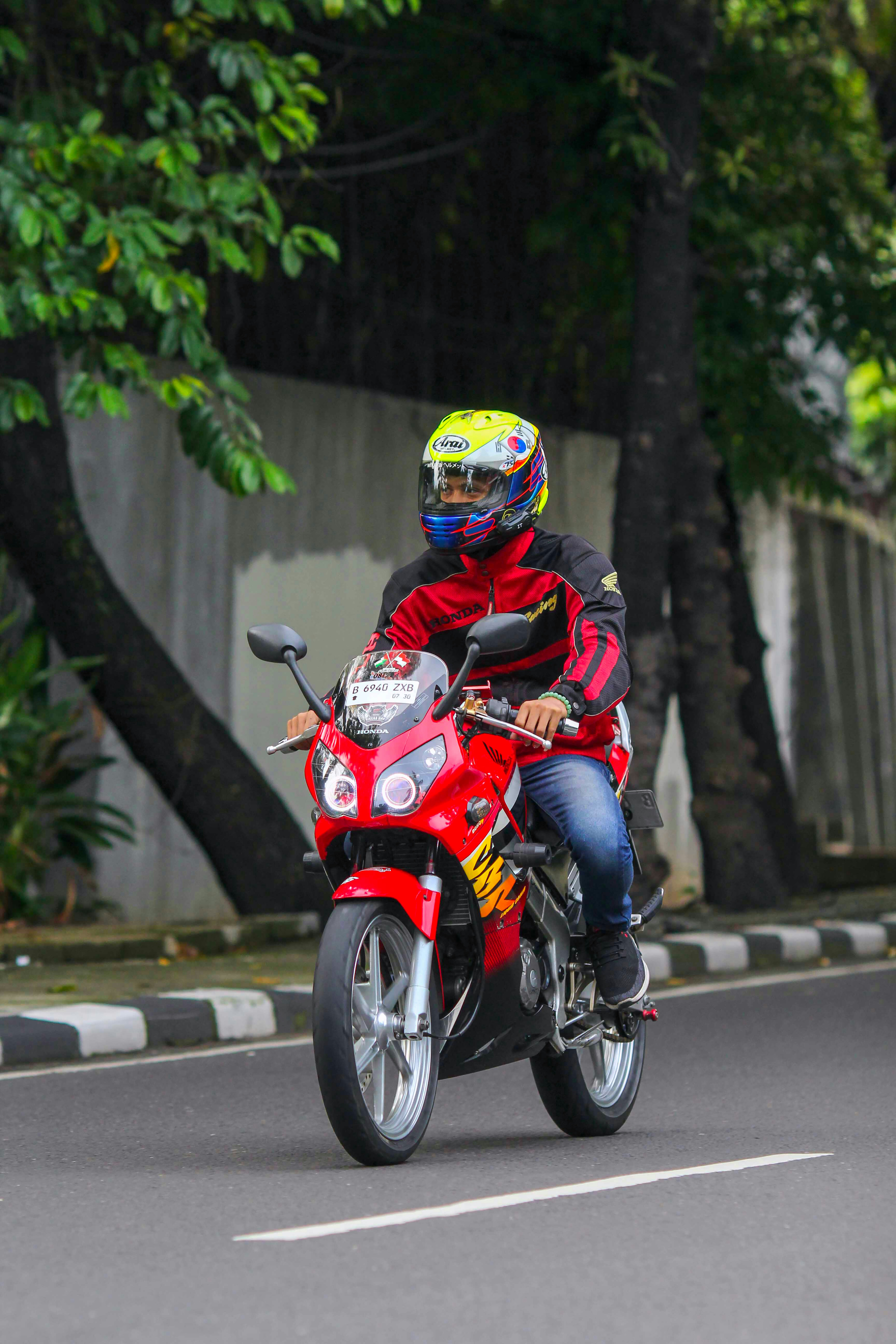 Man in helmet riding a red motorcycle on road