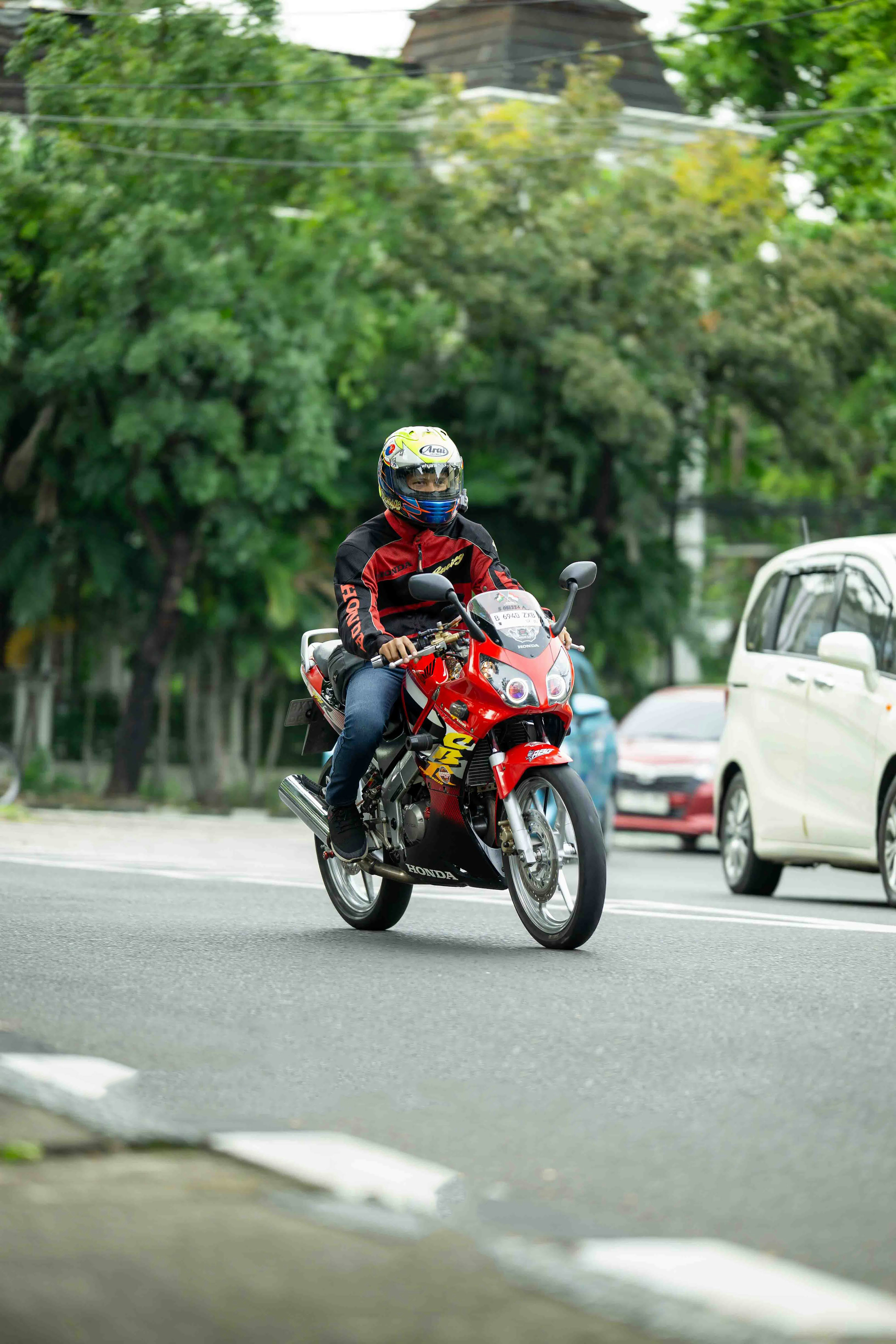 A person riding a red motorcycle on a street.
