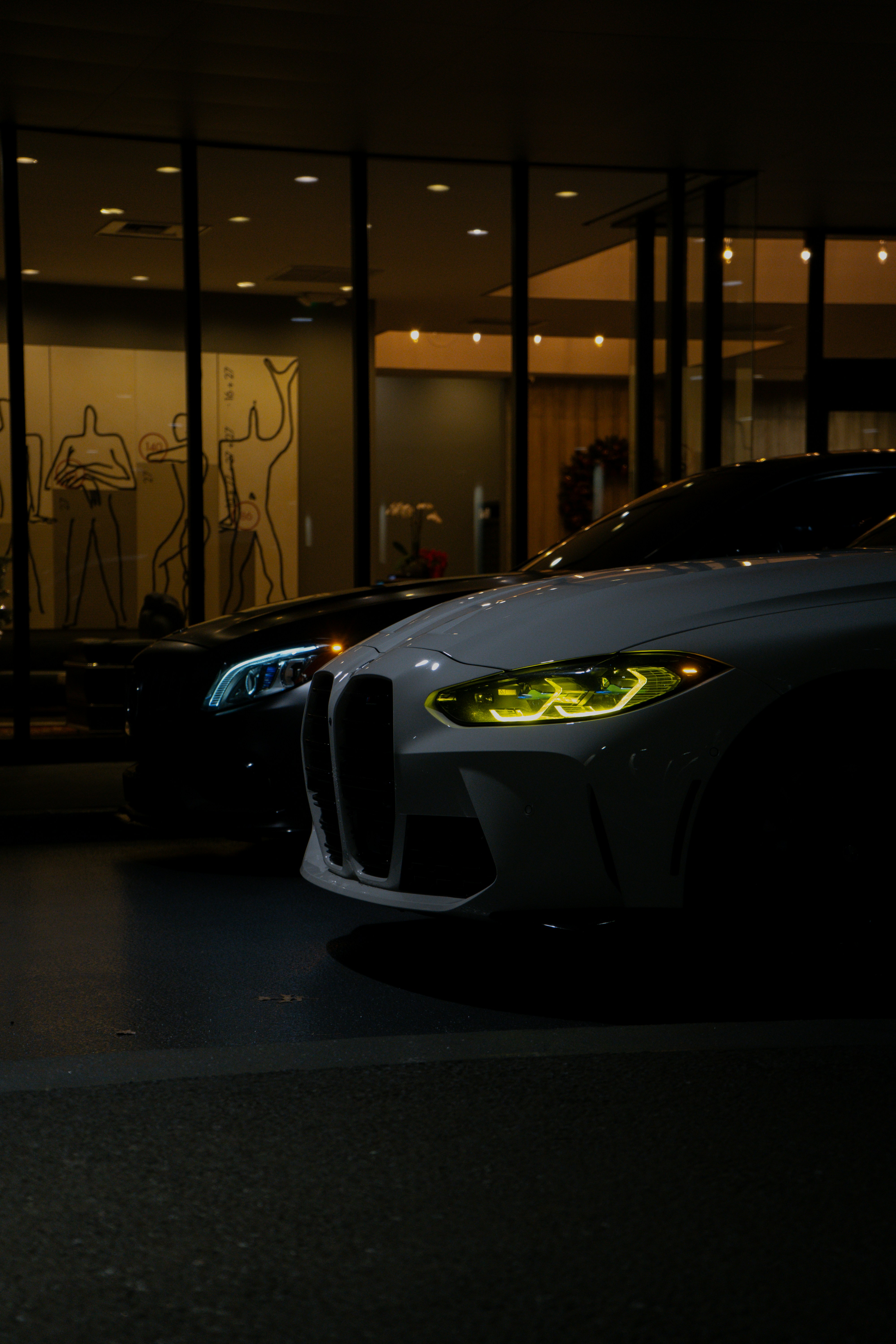 Two cars parked in front of a building at night.
