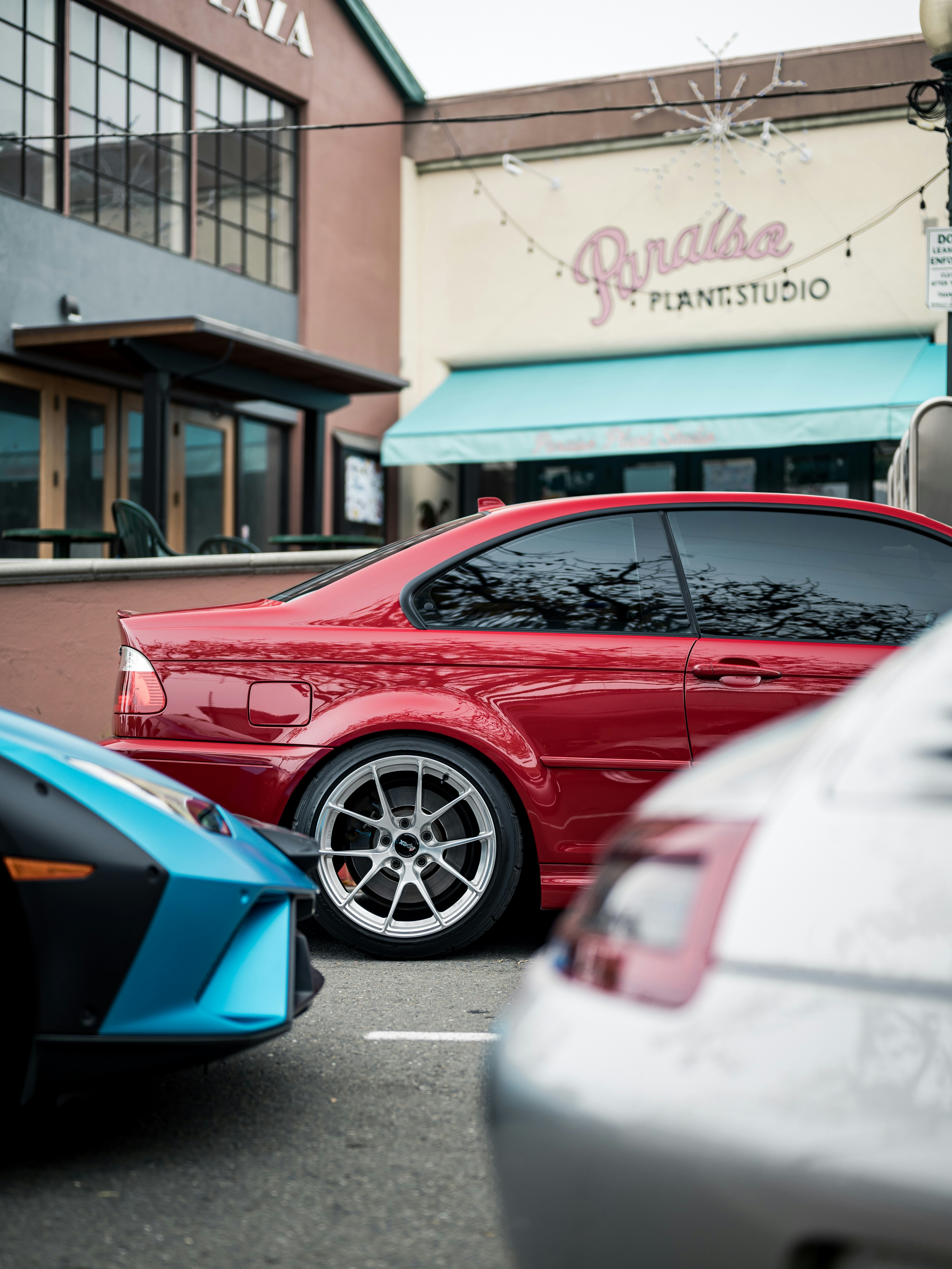 Red sports car parked next to blue and silver cars.