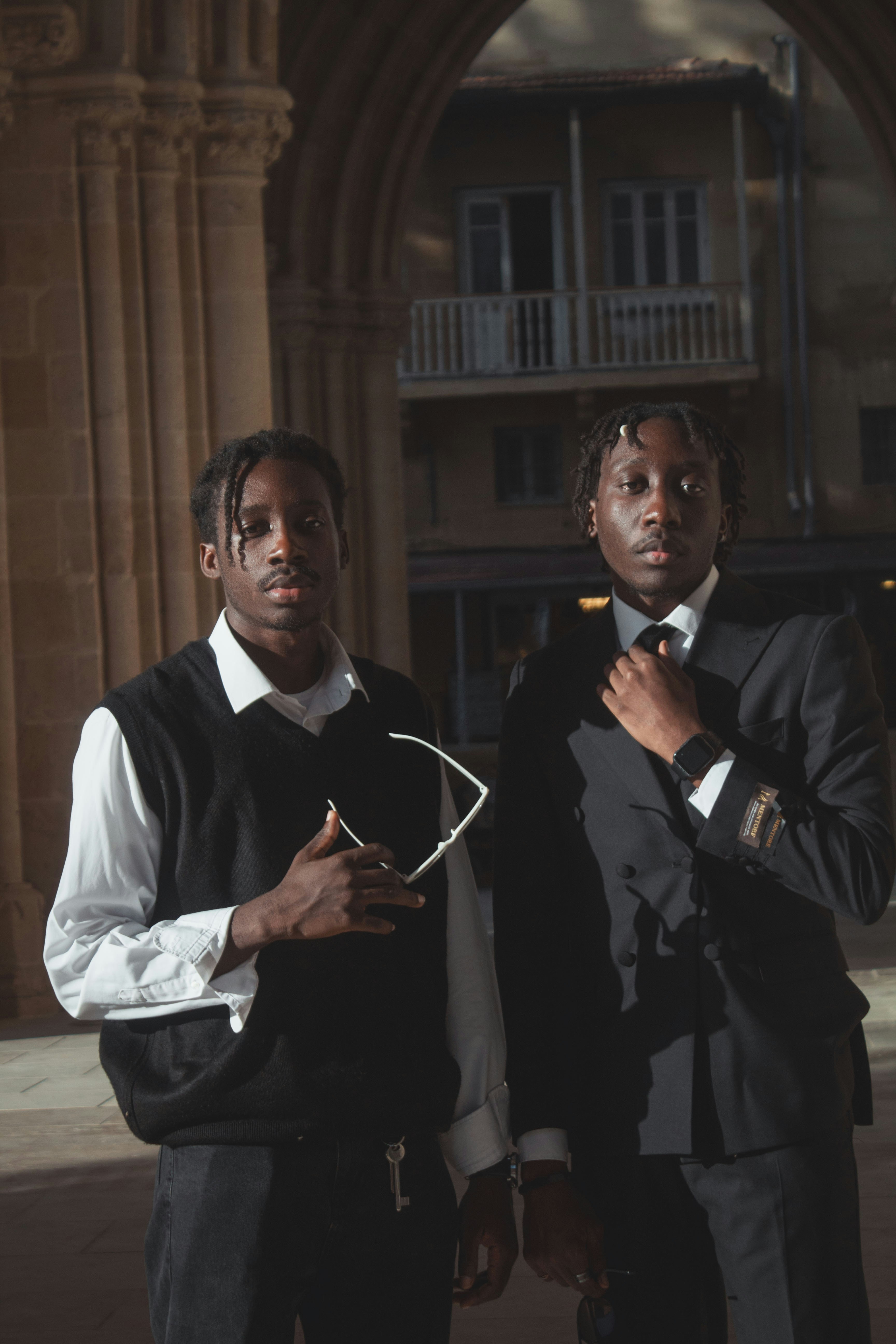Two young men stand in an arched entryway.