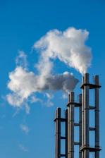 Smoke billows from industrial chimneys against a blue sky
