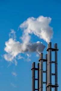 Smoke billows from industrial chimneys against a blue sky