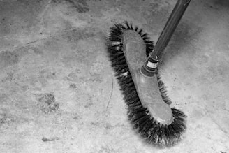 A stiff-bristled brush on a concrete floor