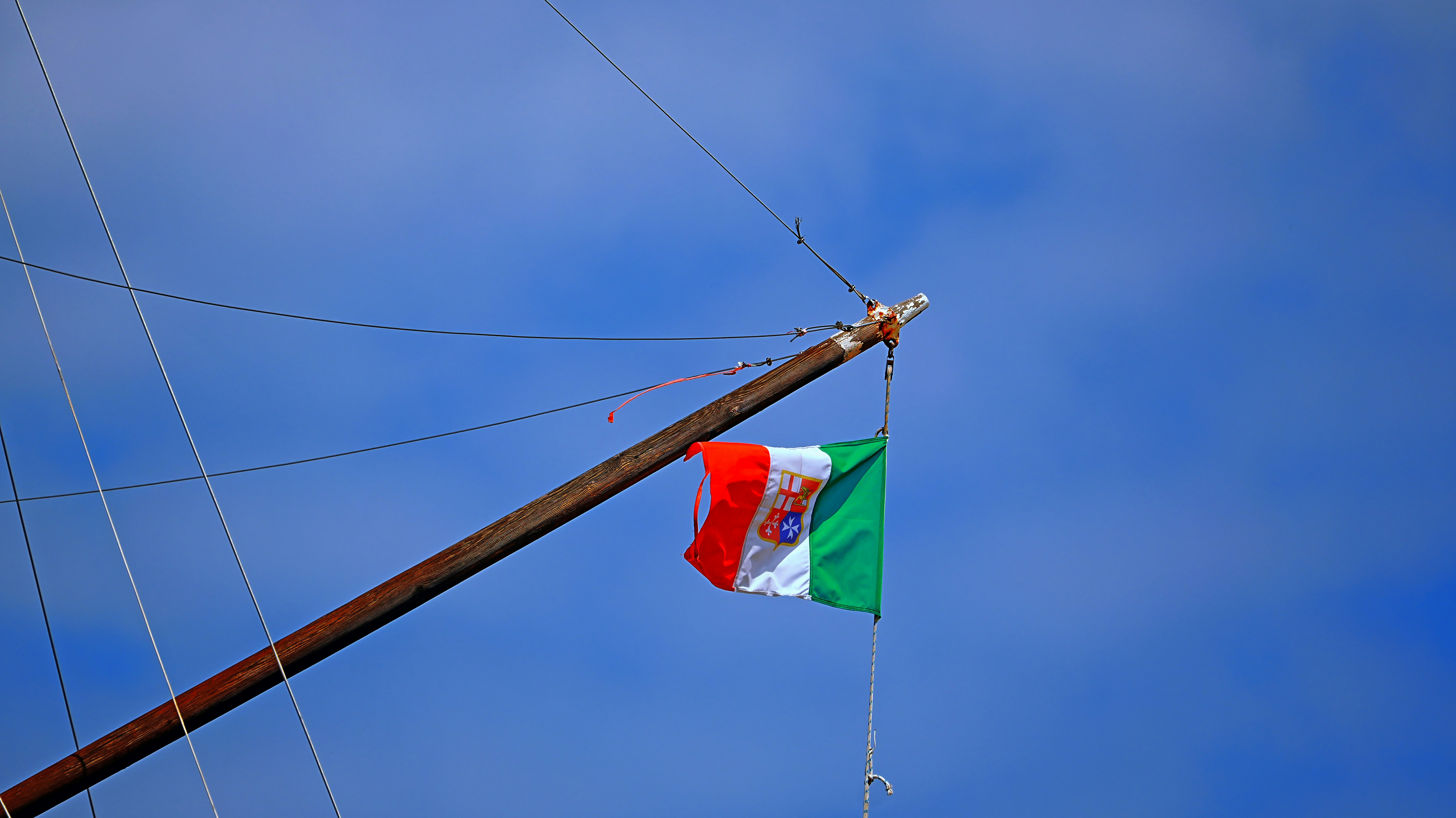 Italian flag waving on a mast against blue sky