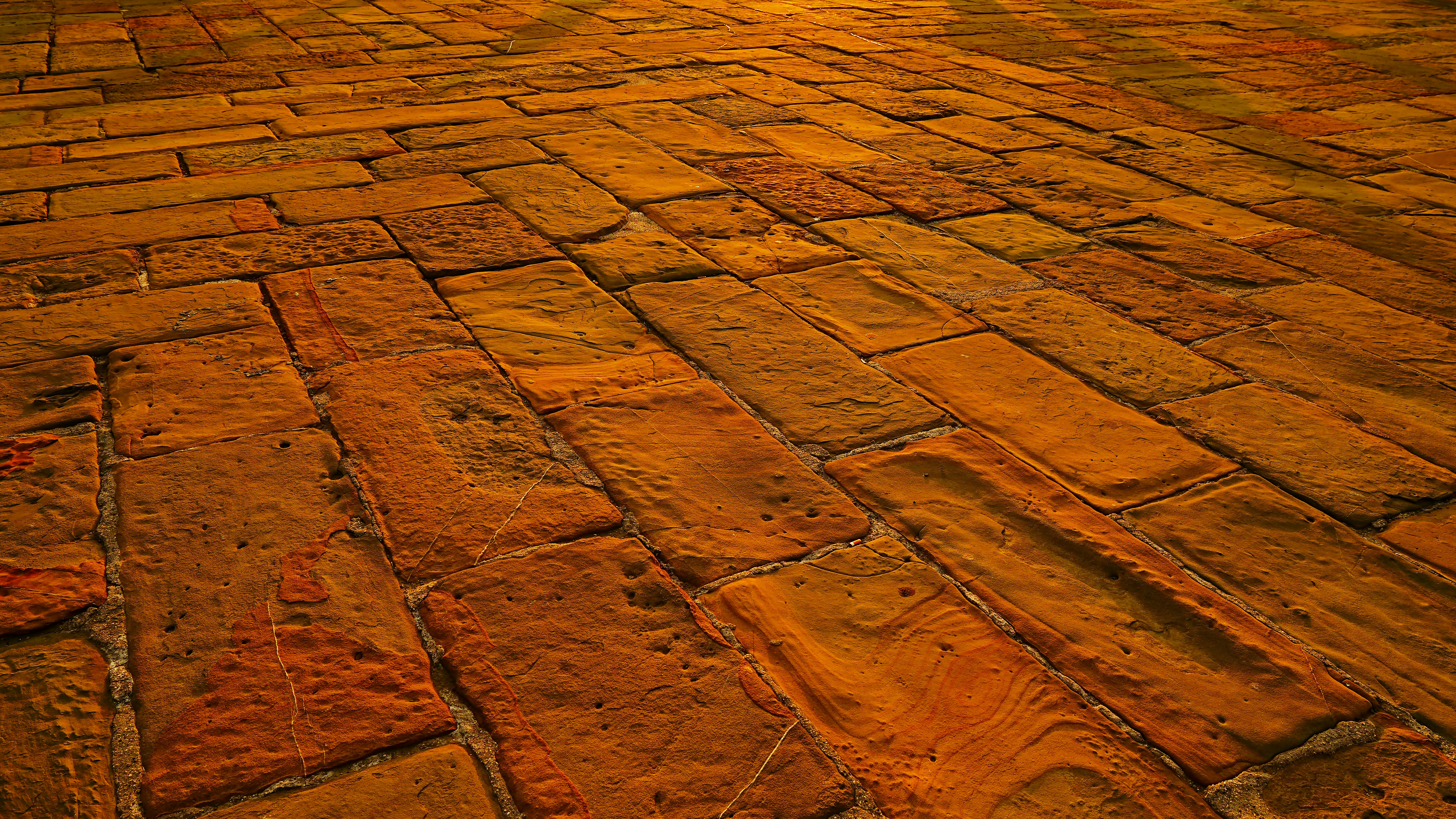 A classic red clay paver walkway winding through a lush green backyard - backyard brick design